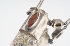 Close-up of eye-shaped Red Kyanite and Dravite Tourmaline set in an oxidized sterling silver Himalayan Quartz pendant.
