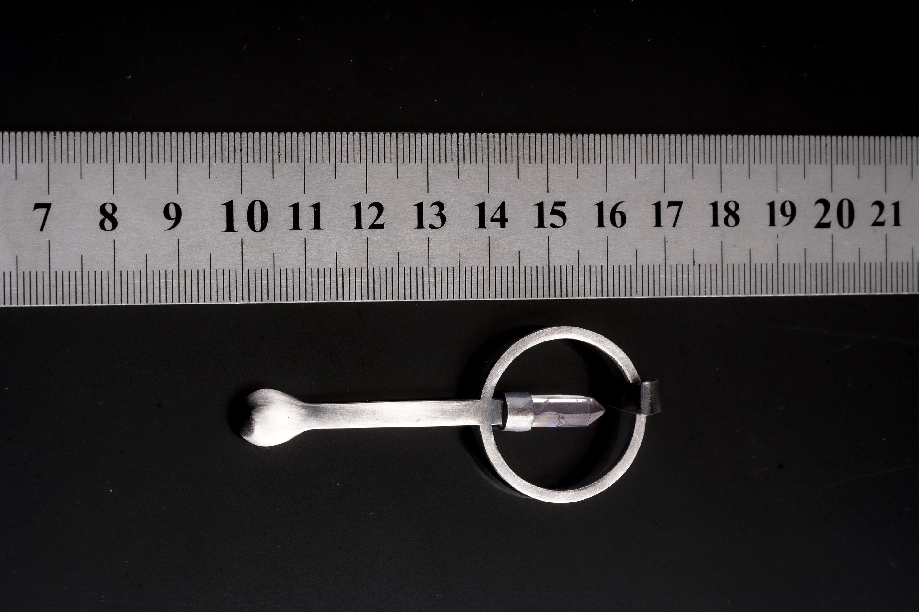 Clear Quartz Generator ritual spoon pendant shown beside a ruler for scale with hammered sterling silver body.