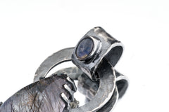 Close-up of Blue Moonstone and Black Rutile Quartz pendant showing dark oxidized silver bail and moonstone glow.