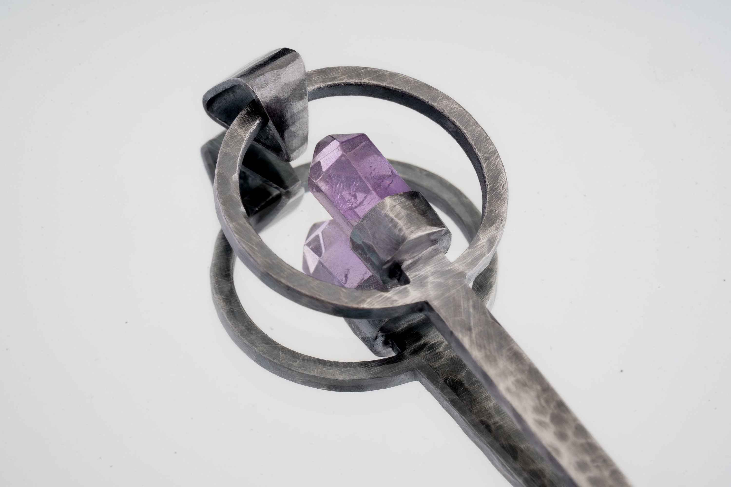 Close-up of Amethyst Generator ritual spoon showing textured sterling silver setting and cut purple crystal point.