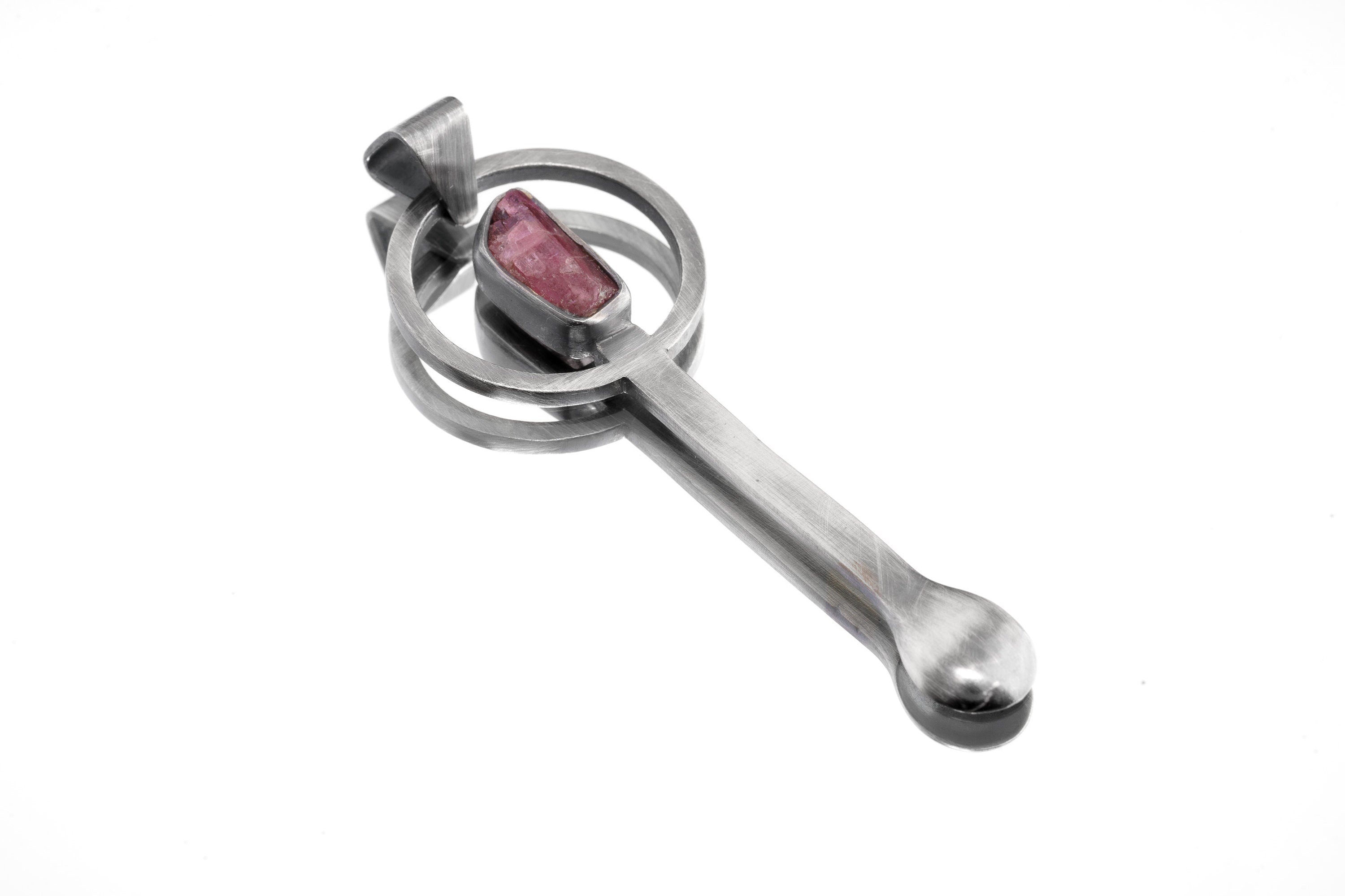 Rubellite Tourmaline sterling silver brushed spoon pendant shown on white background with red-pink stone and sculptural silver form.