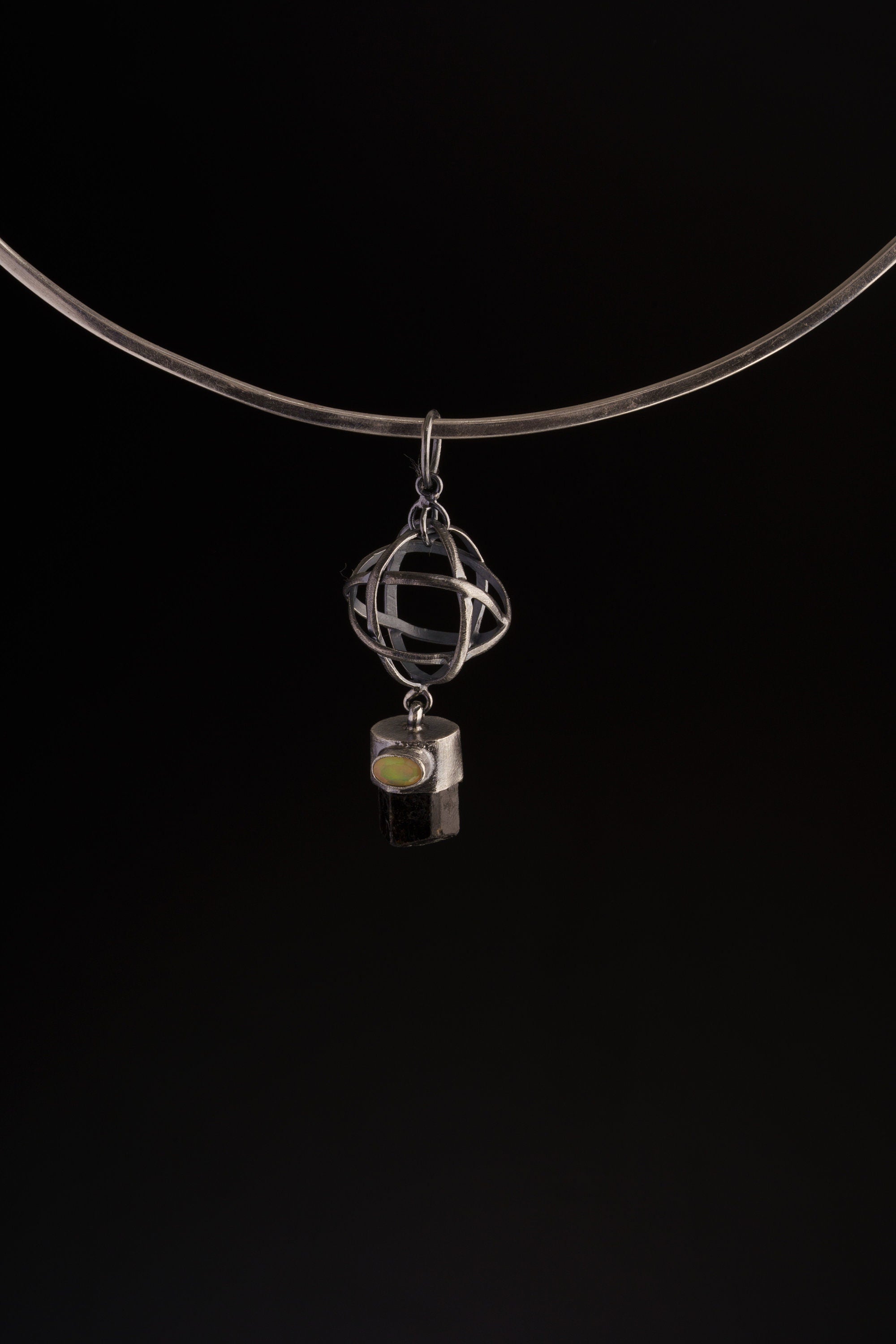 Brown Tourmaline and Ethiopian Opal sphere pendant shown on a black cord, with open oxidized silver wire sphere design.