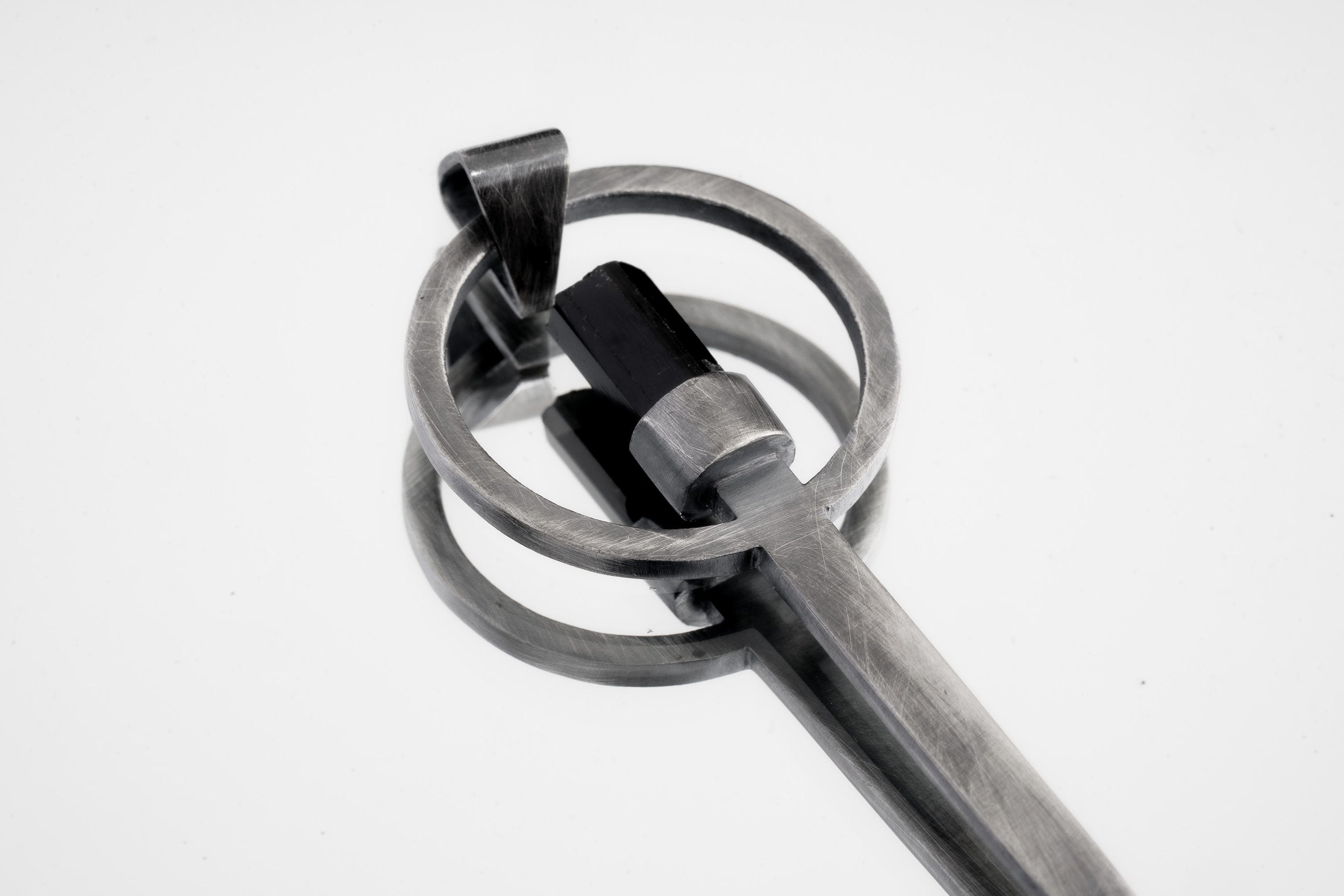 Close-up of Black Tourmaline spoon pendant showing hammer-textured sterling silver and protective dark stone.
