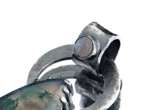 Close-up of Moss Agate set into the bail of a Blue Moonstone pendant with oxidized silver texture.