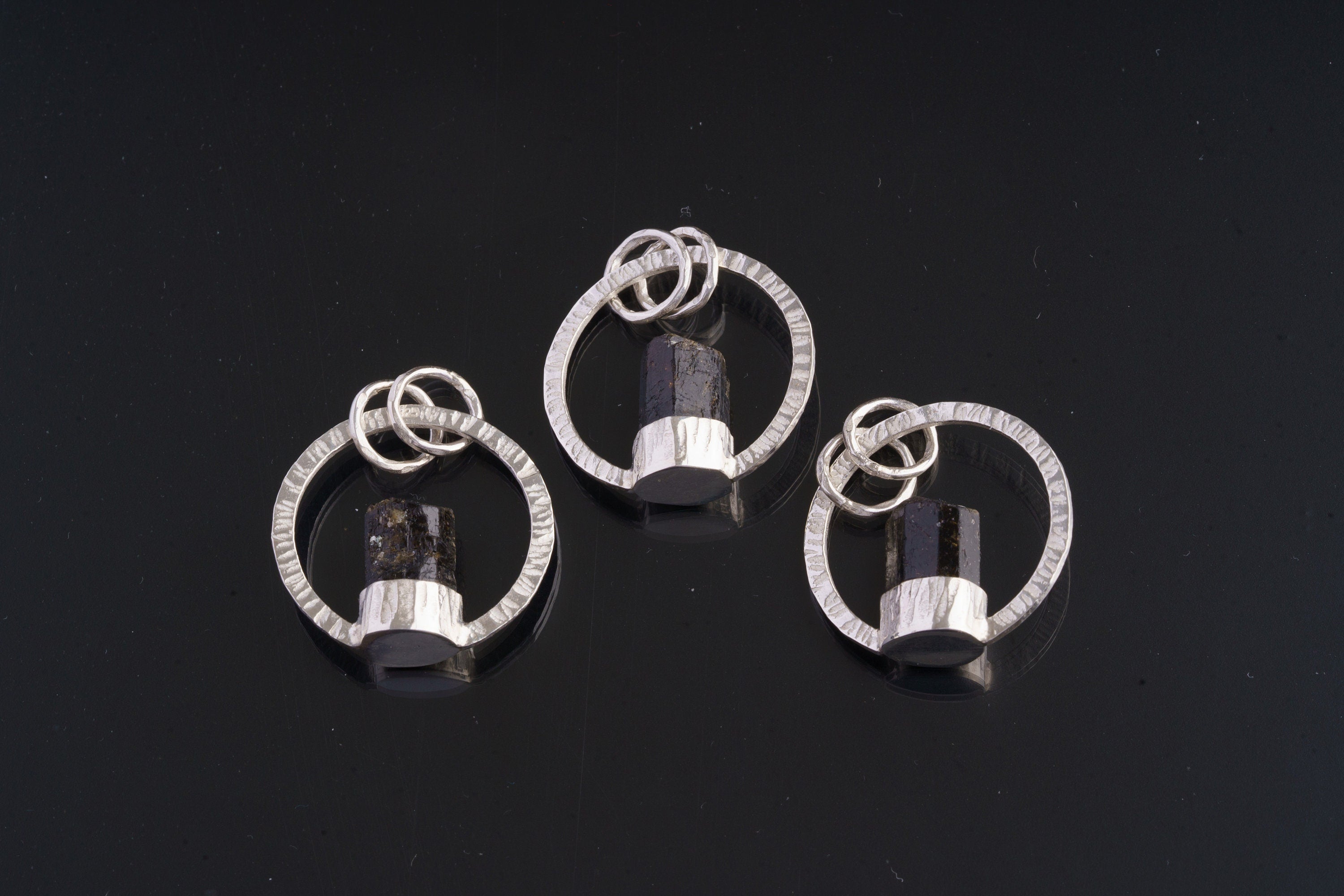 Three handmade Dravite halo pendants showing circular silver portal design.