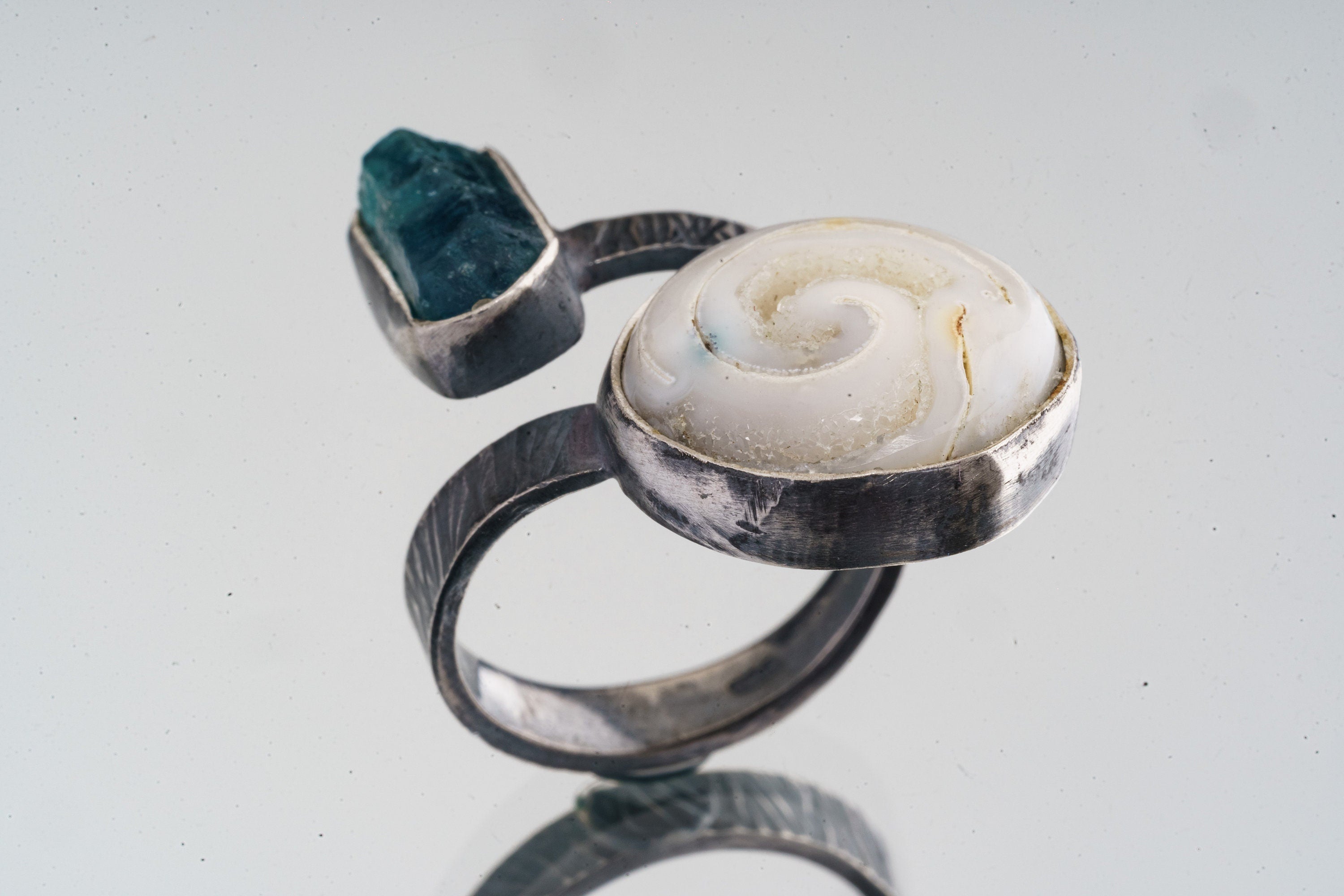Apatite Shell ring shown from the side, with floating dual-stone layout and textured oxidized silver band.