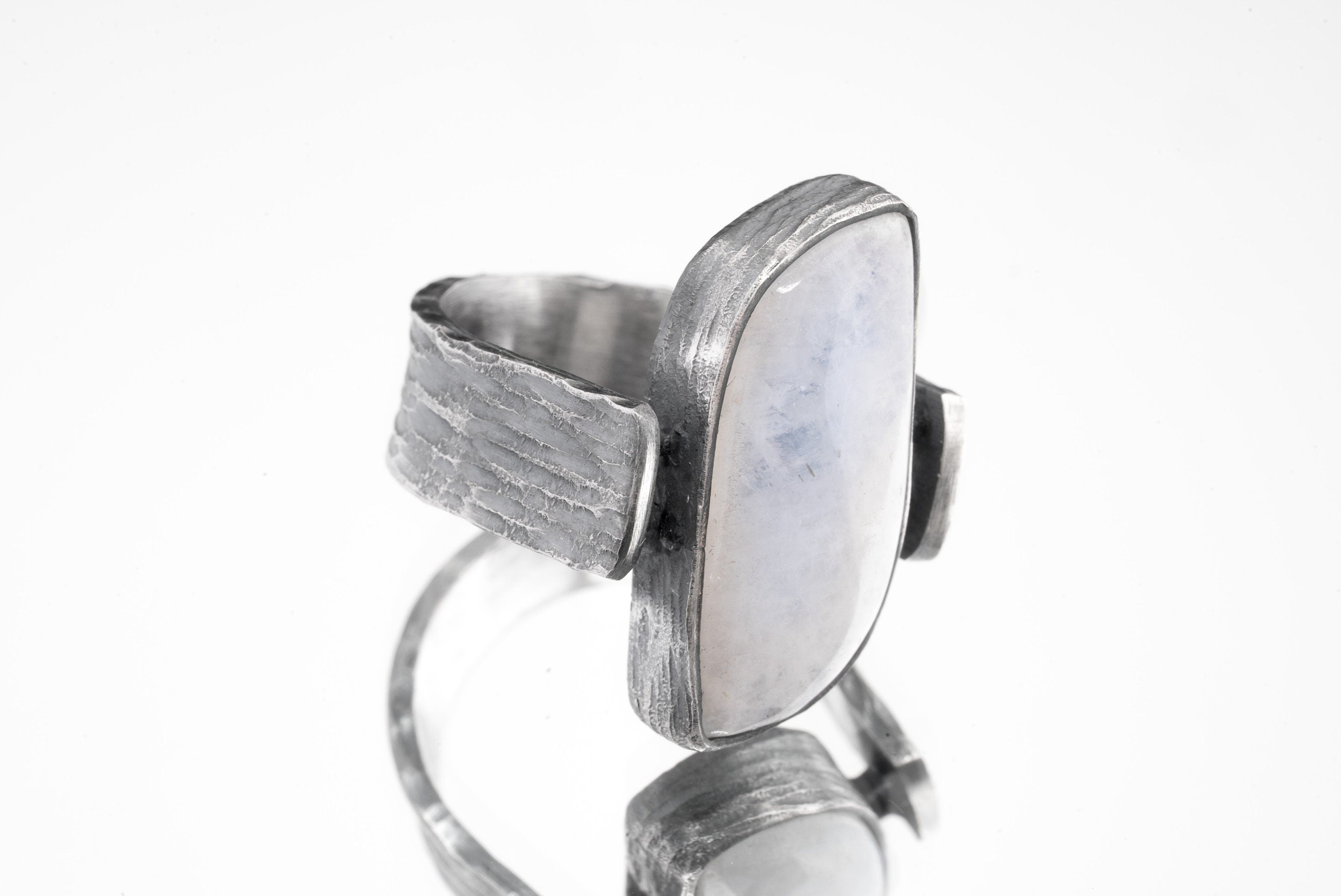 Side view of Moonstone ring showing bark-like oxidized silver texture, coiled supports, and raised rectangular stone.
