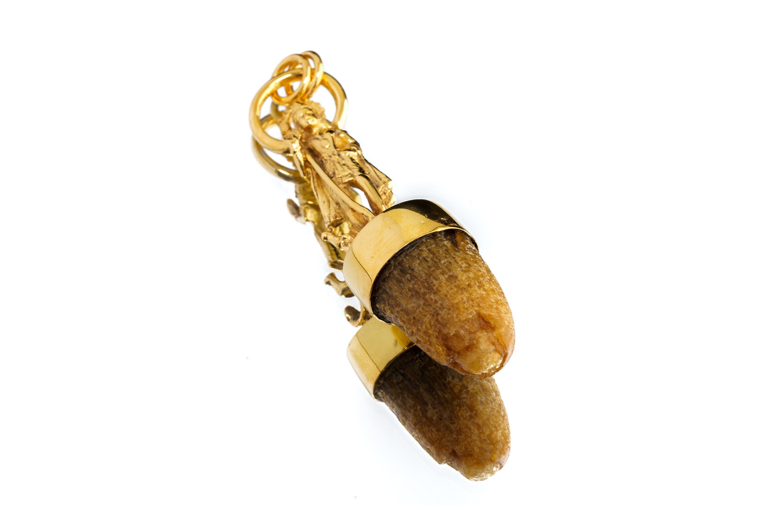Close-up of Shiva cow horn pendant showing brass cast deity figure, gold plating, and natural horn detail.