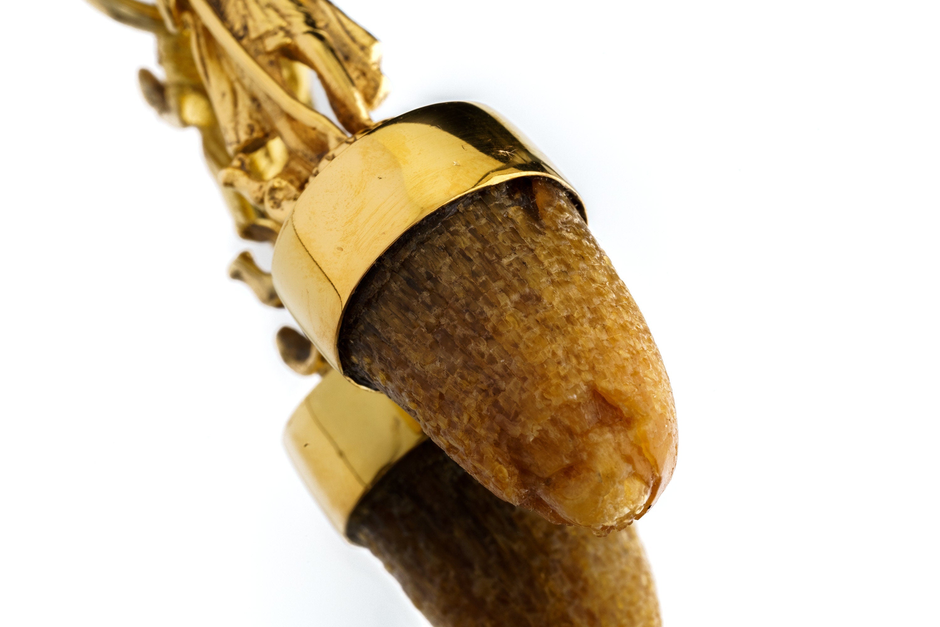 Close-up of natural cow horn beneath gold-plated Shiva figure with textured sterling silver joining bezel.