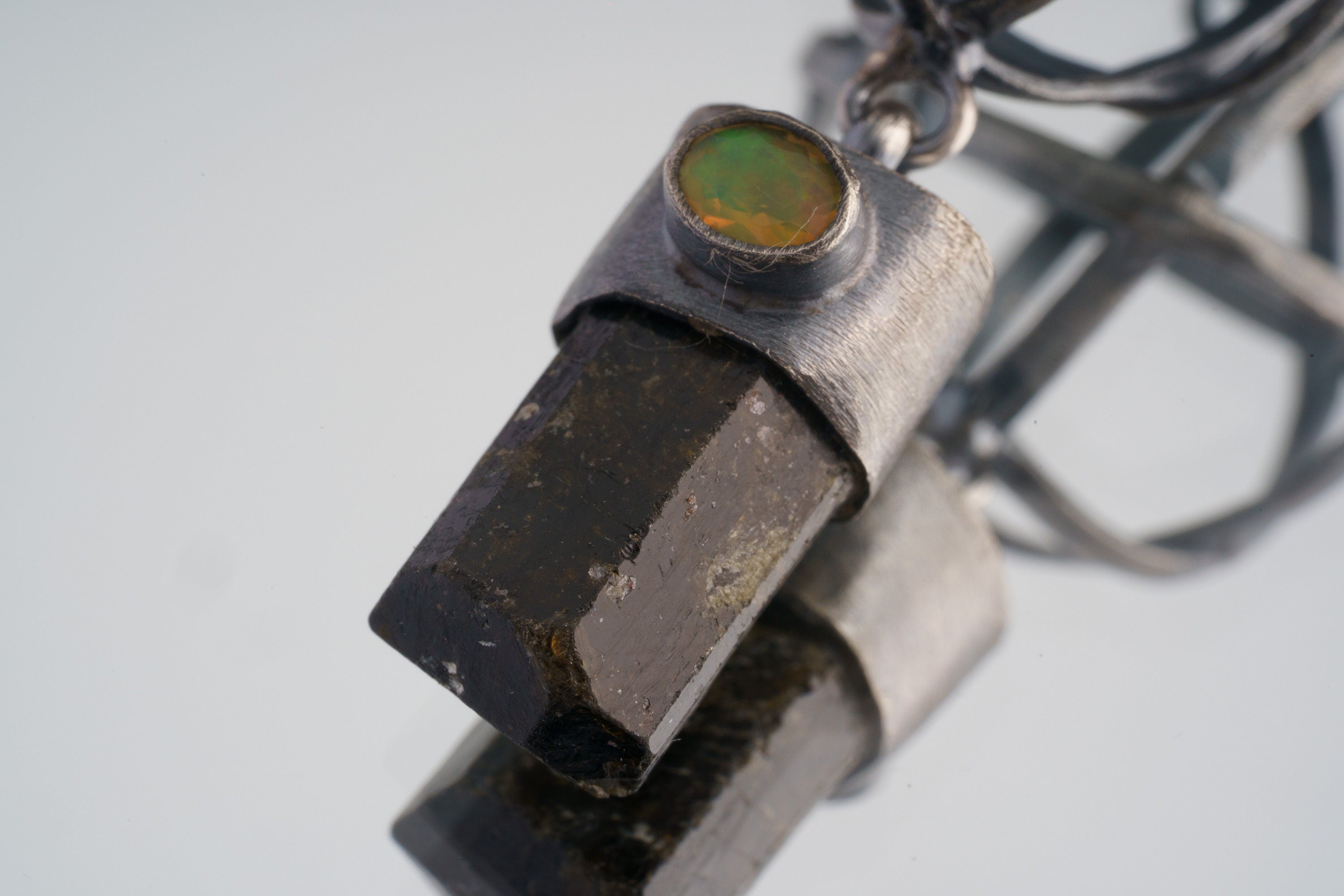 Close-up of Himalayan Brown Tourmaline pendant with fiery Ethiopian Opal and dark oxidized silver sphere construction.