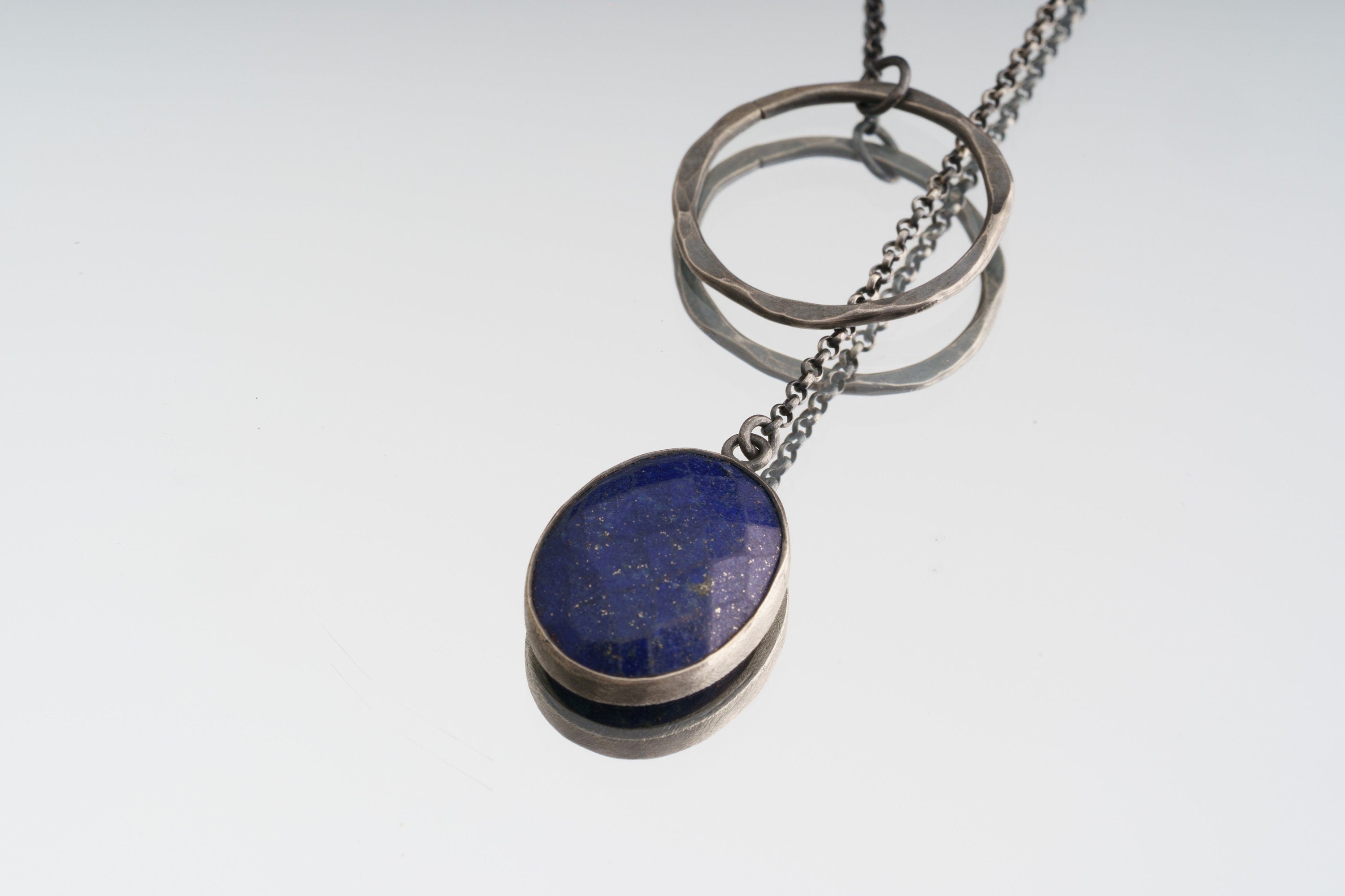 Faceted Lapis Lazuli necklace on white background with open-back sterling silver bezel and adjustable lariat chain.