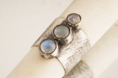 Close-up of antique bone tube pendant showing textured 925 sterling silver band and three Blue Moonstone settings.
