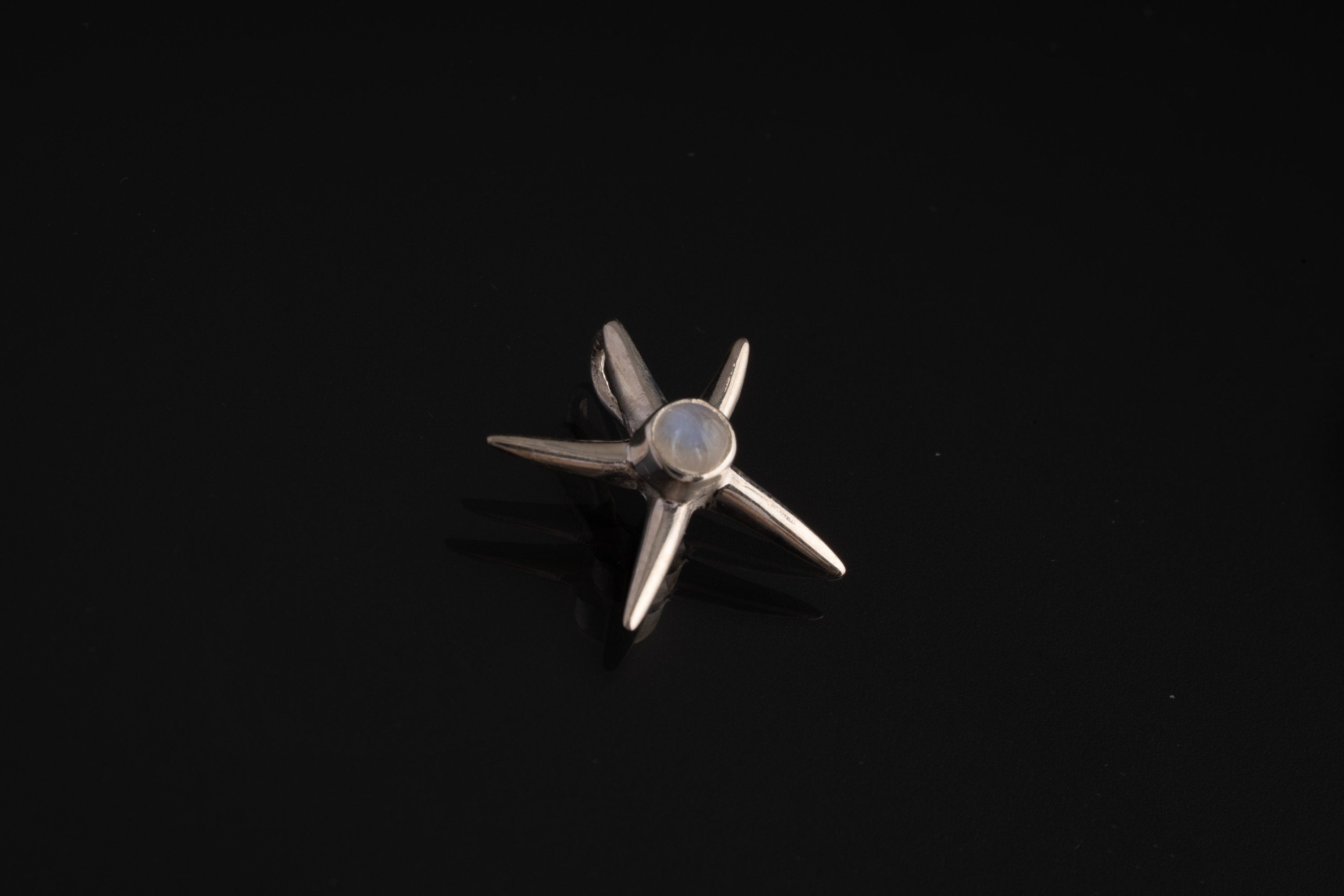 Blue Moonstone starfish charm shown hanging on black cord, with high-shine sterling silver and ocean talisman design.