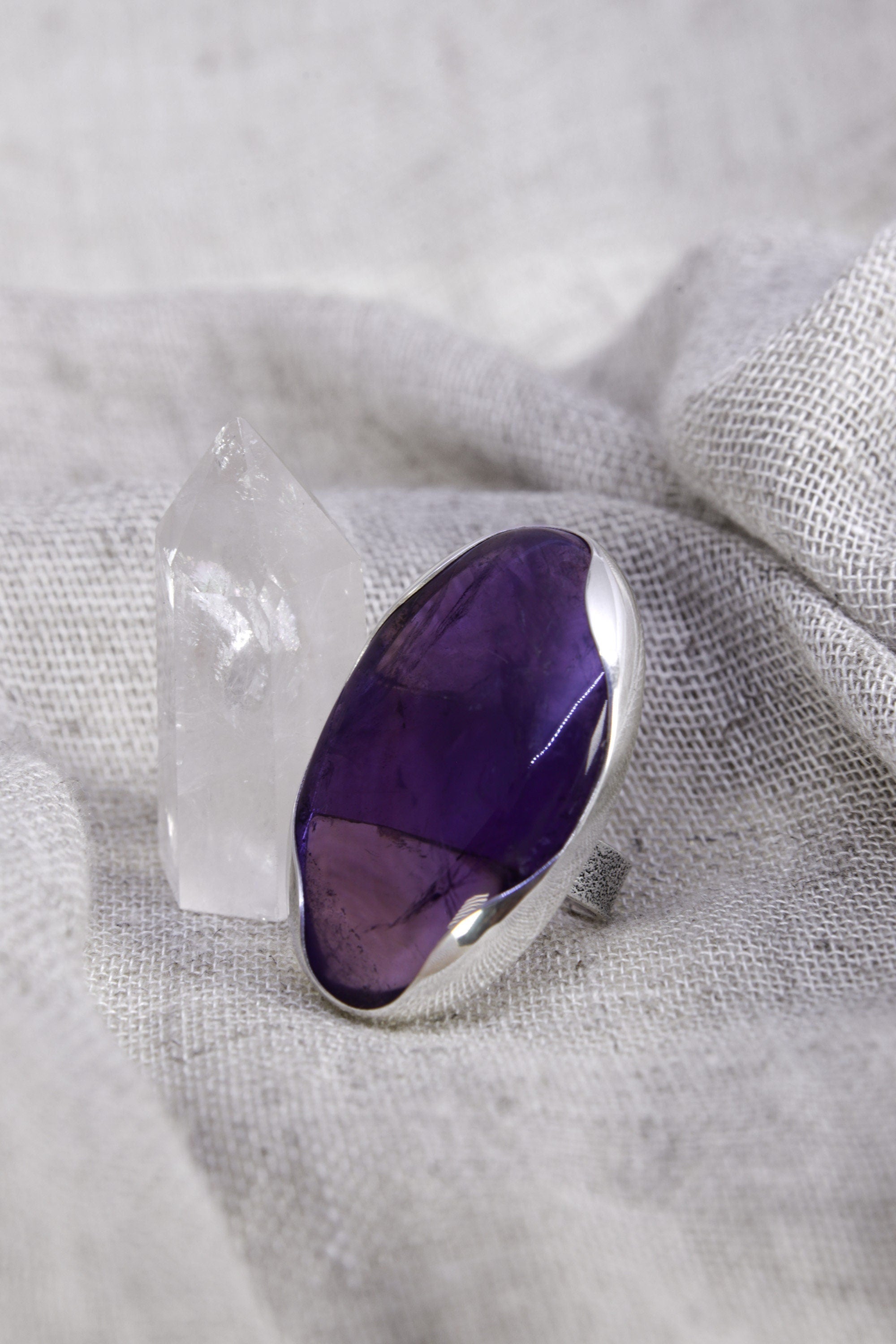Oval Amethyst adjustable ring in high-shine 925 sterling silver shown on soft fabric with a polished purple gemstone.