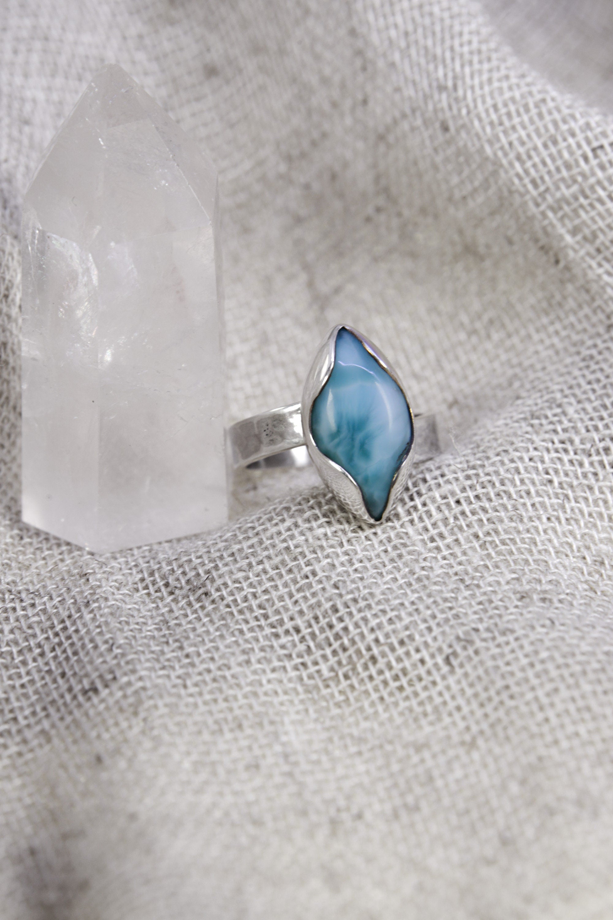 Larimar adjustable ring shown beside a quartz crystal, with high-shine sterling silver and ocean-blue eye-shaped stone.