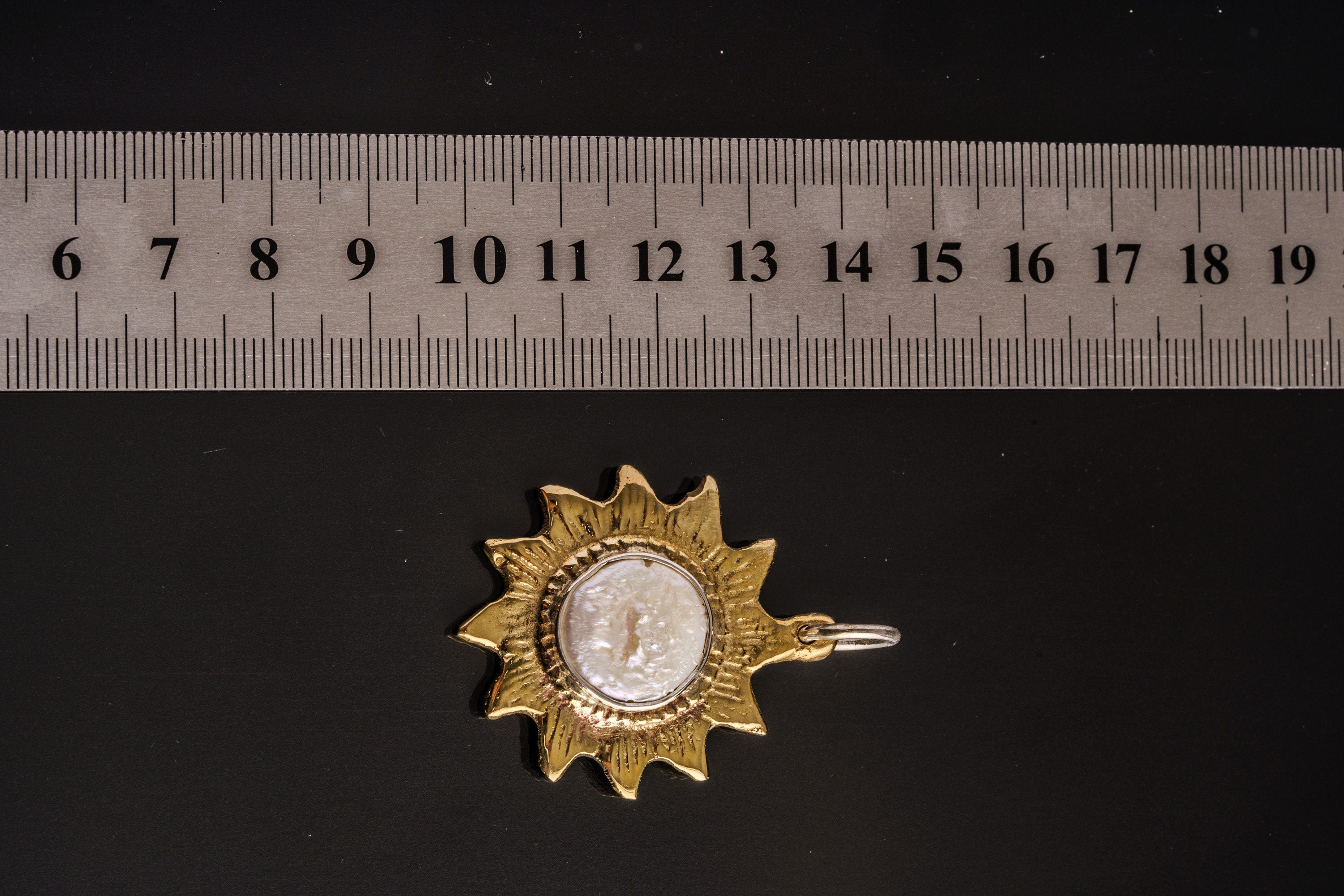 Gold-plated brass sun and Mother of Pearl pendant shown beside a ruler for scale, measuring approximately 4 to 4.5 cm across including bail.