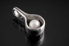 Polished sterling silver Pearl spinner pendant with luminous white Pearl sphere inside a sculptural silver wrap.