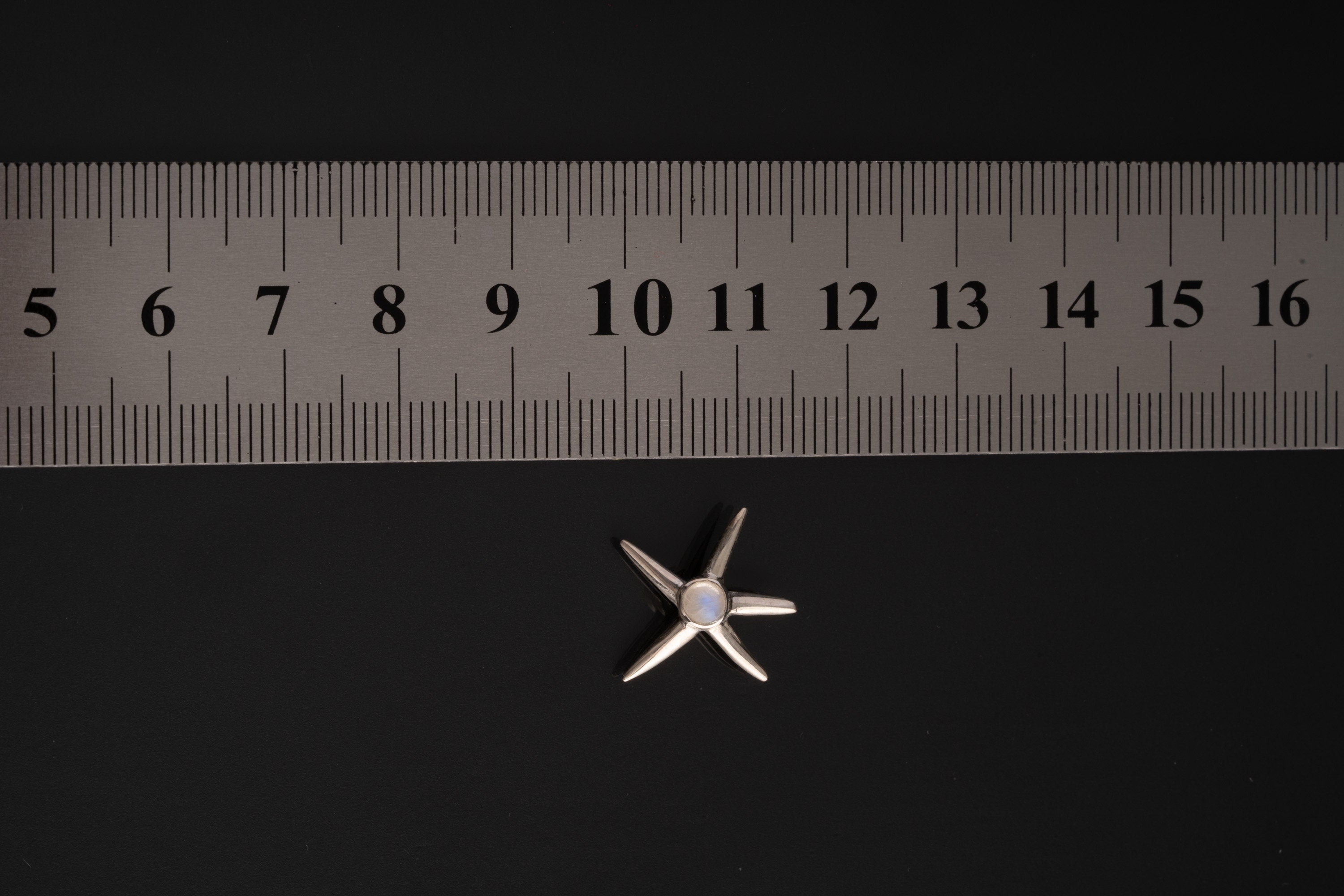 Blue Moonstone starfish charm shown beside a ruler for scale, measuring approximately 2.5 cm.