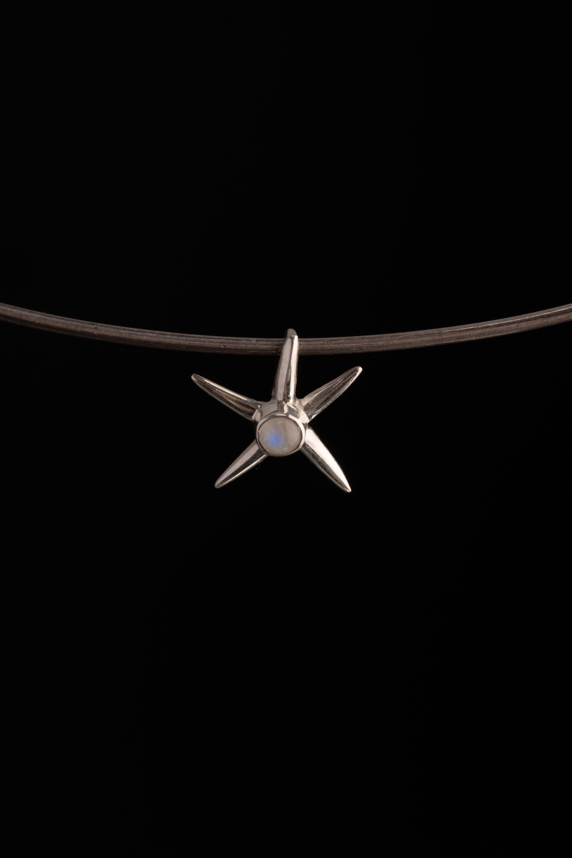 Close-up of polished sterling silver starfish charm with natural Blue Moonstone set at the centre.