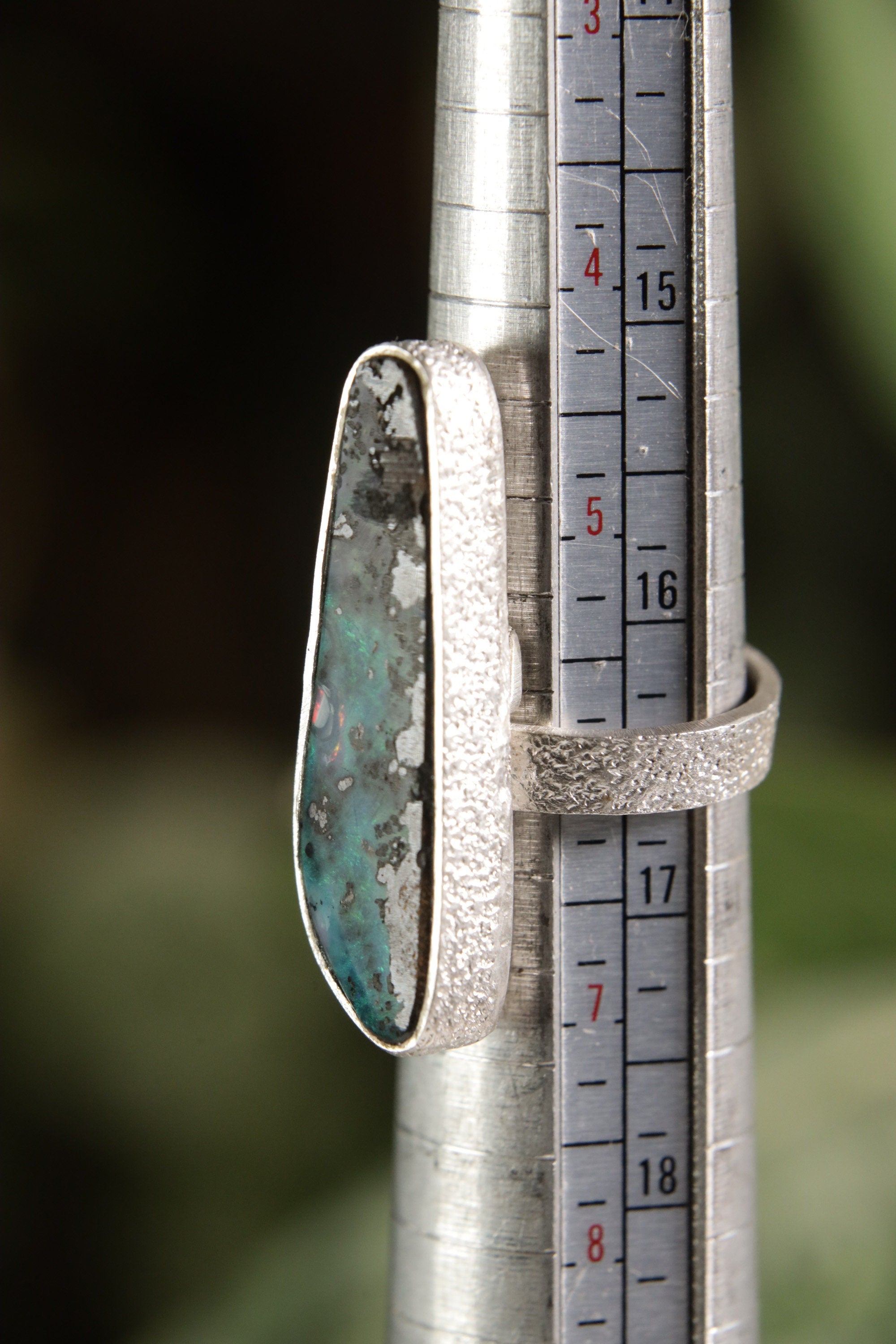 Opal adjustable ring shown beside a ruler for scale, with high-shine 925 sterling silver band and waved bezel setting.