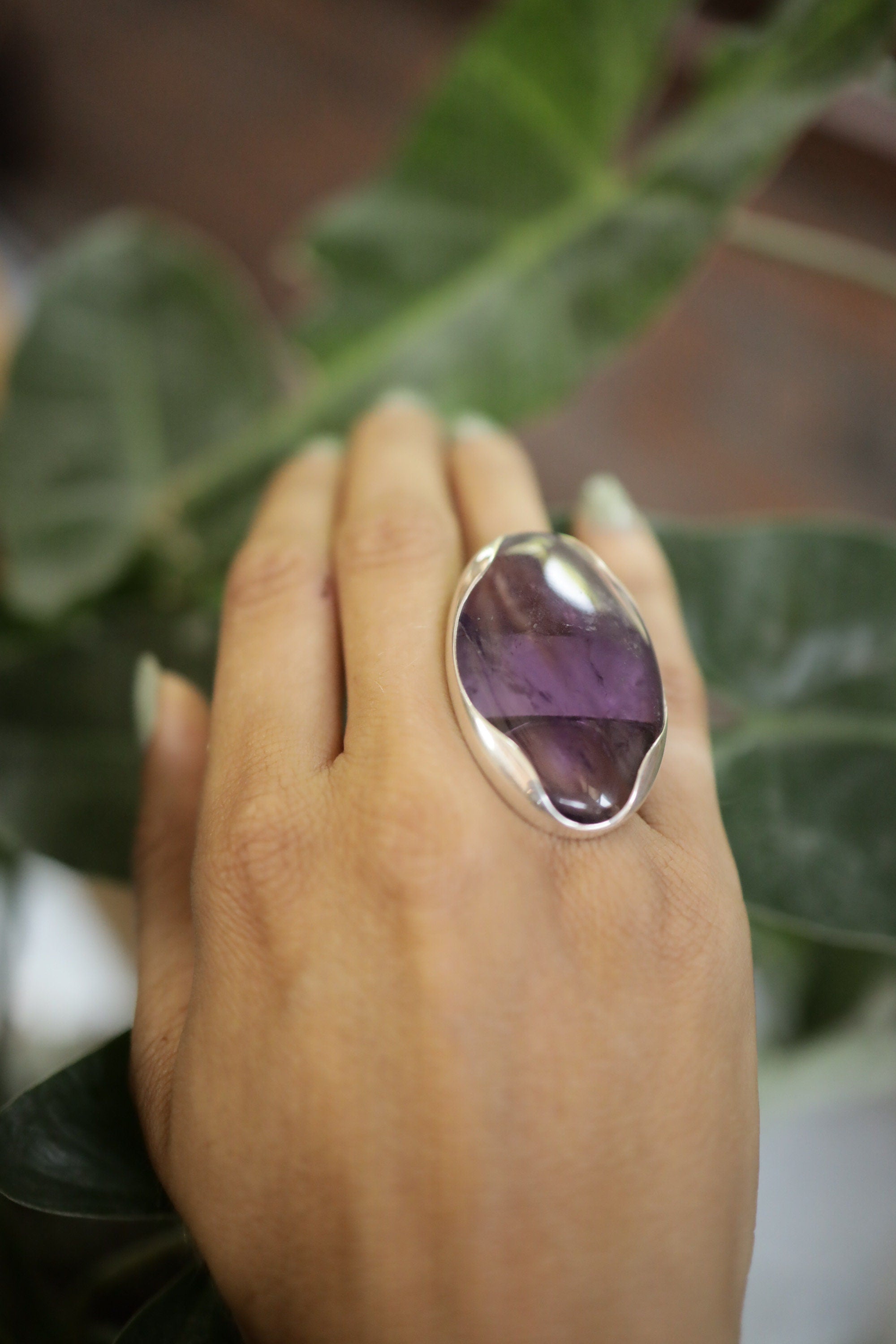 Oval Amethyst adjustable ring shown worn outdoors, with purple gemstone and textured sterling silver band.