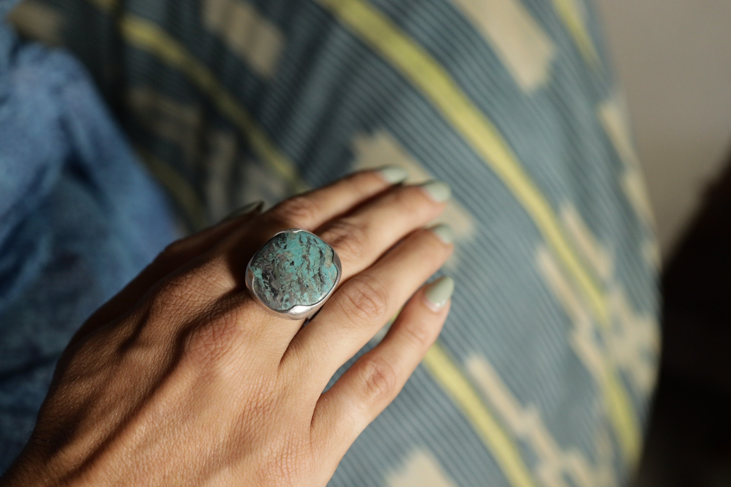 Australian Turquoise ring shown worn on the hand, with textured sterling silver band and blue-green stone surface.
