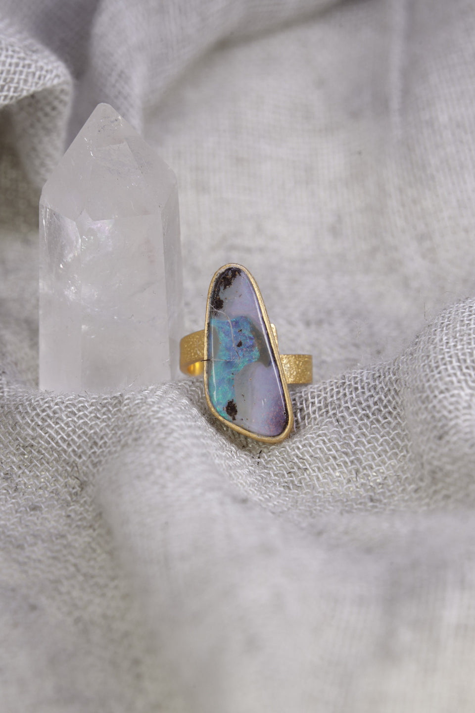 Gold-plated Opal ring shown on soft fabric, with waved bezel setting and warm 18k gold-plated sterling silver band.