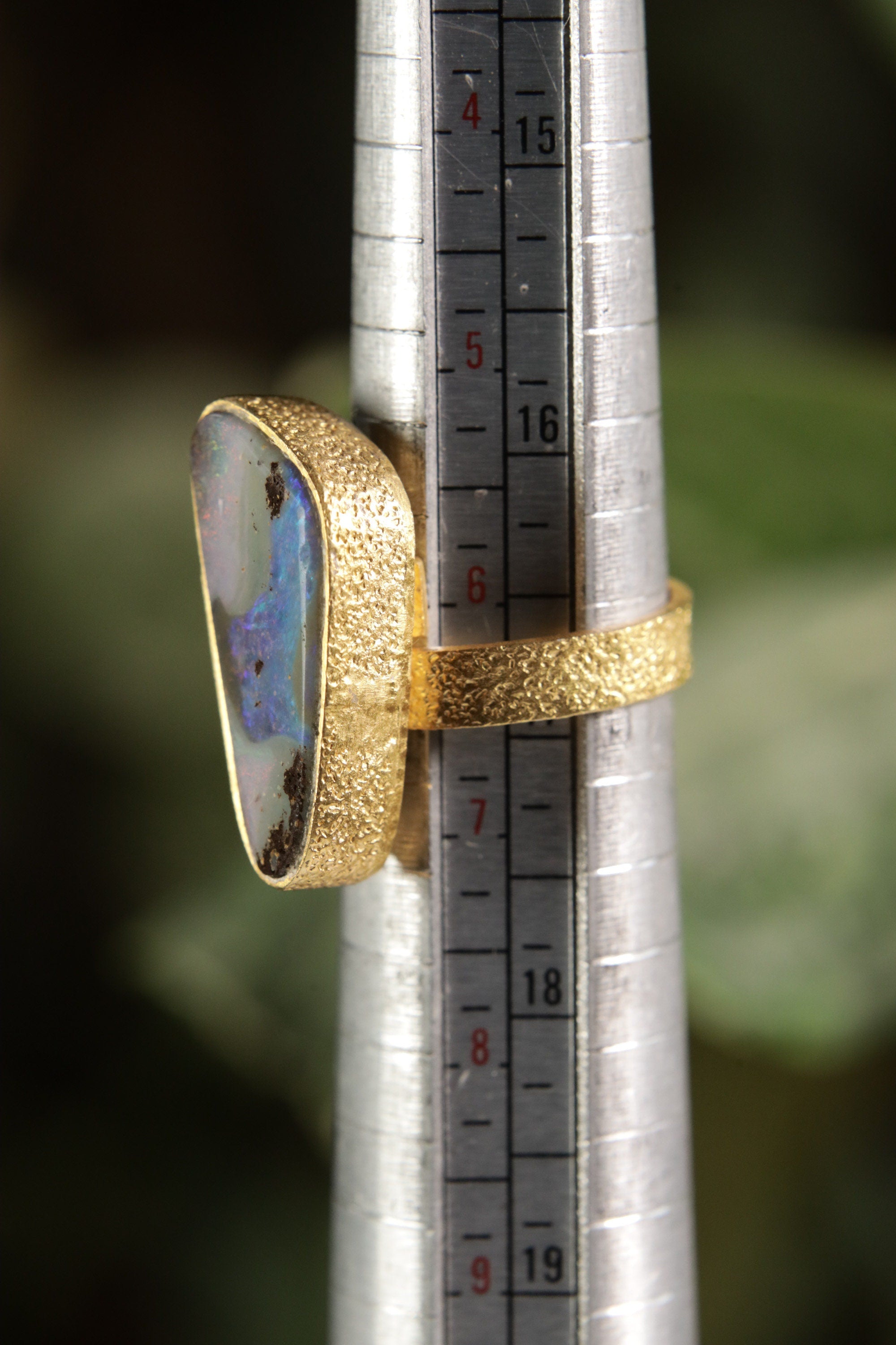 Opal gold-plated ring shown beside a ruler for scale, with adjustable open band and warm handmade silver setting.