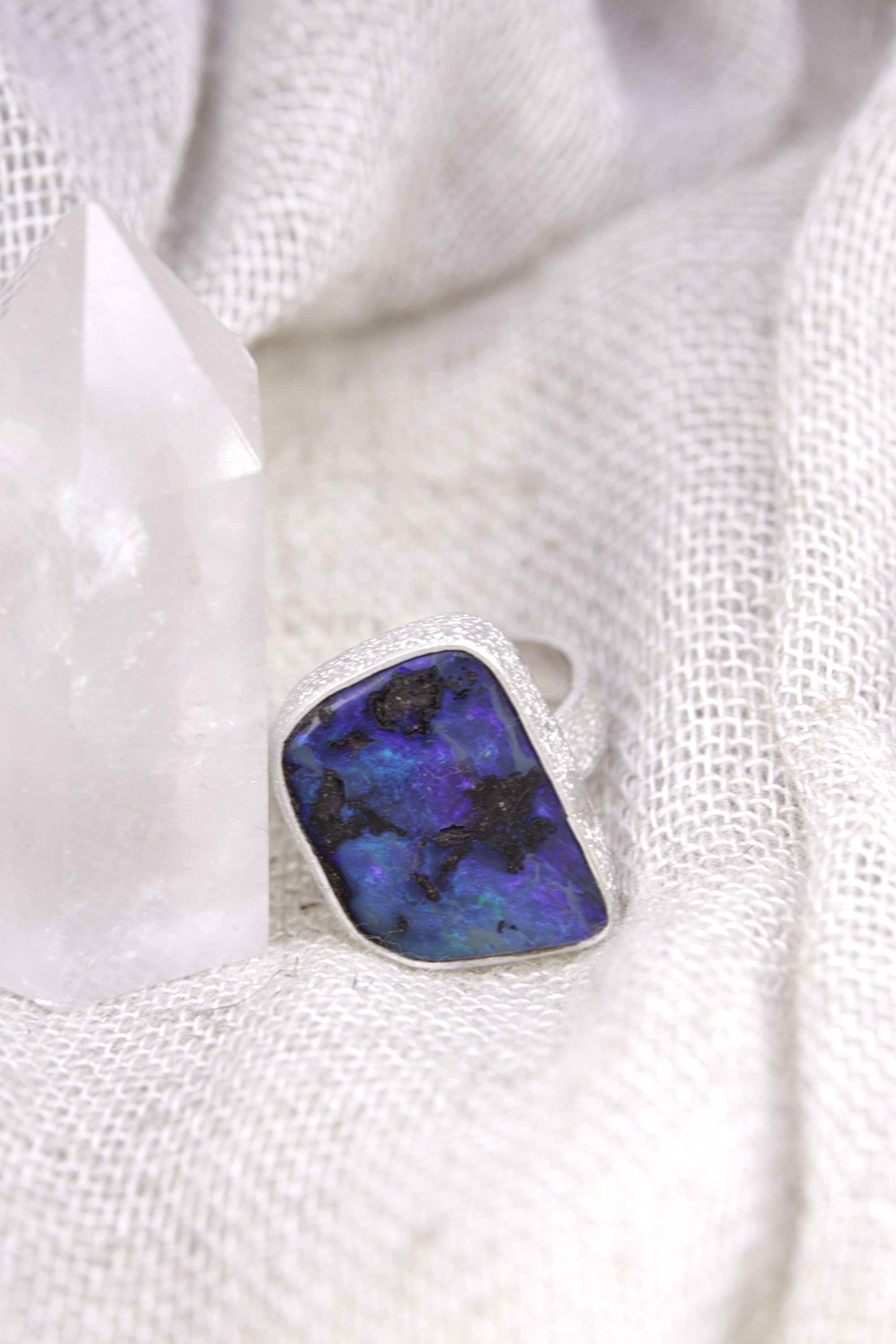 Square Opal adjustable ring shown beside a quartz crystal, with waved bezel setting and polished sterling silver band.