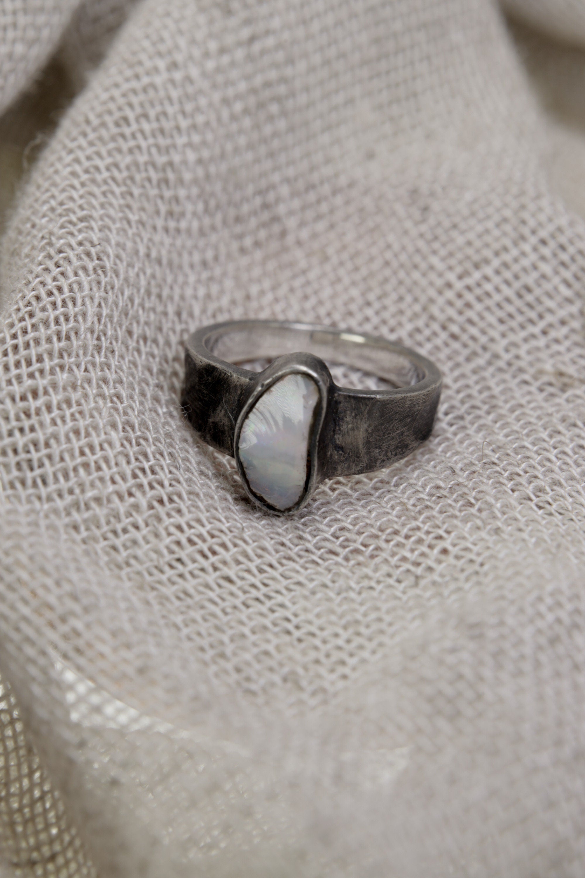 Lightning Ridge Gem Opal ring in handmade sterling silver, shown from the side with textured band detail and pale rainbow opal colour.
