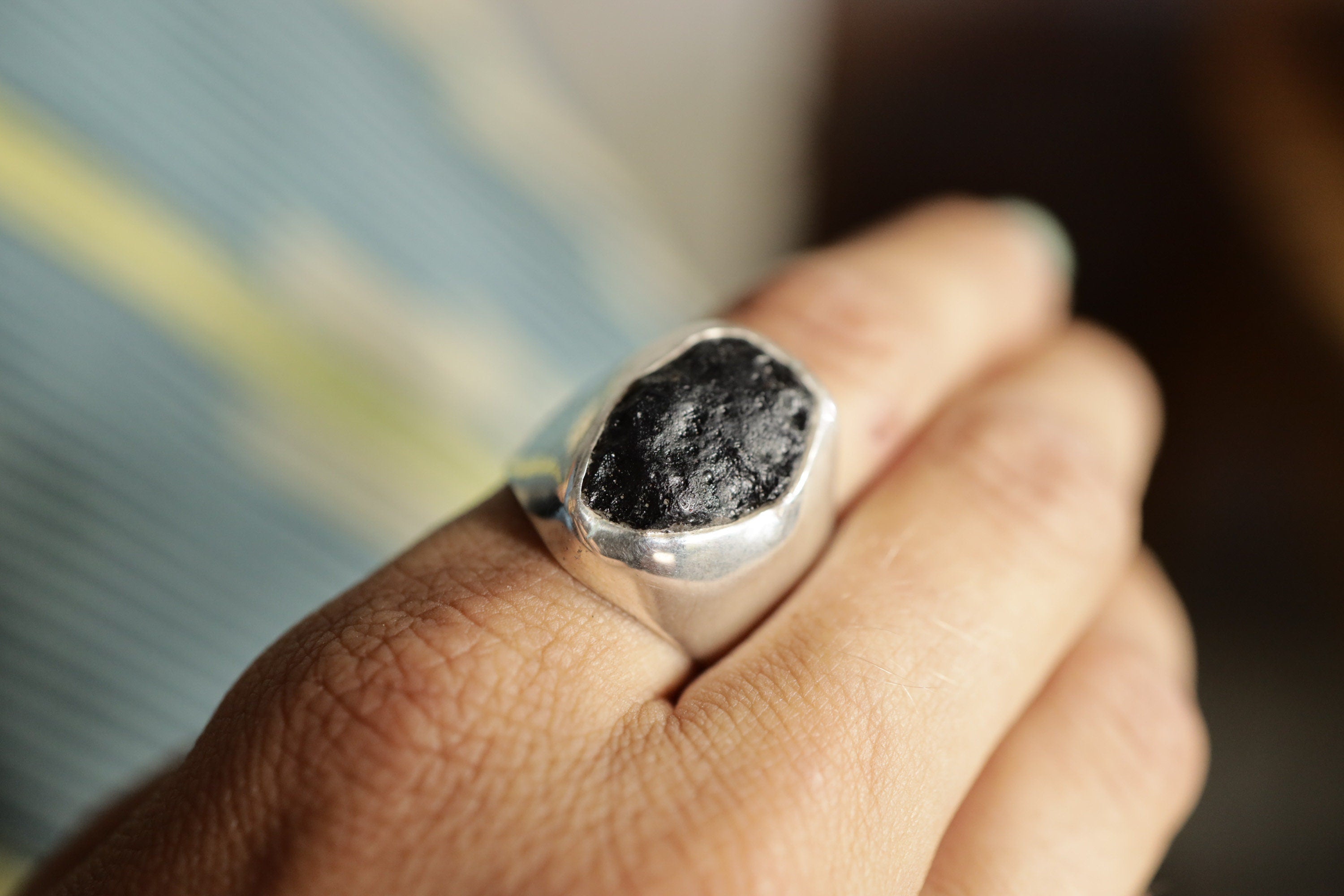 Mount Darwin Tektite Hollow Silver Ring shown worn on hand with rough dark stone and lightweight silver band.