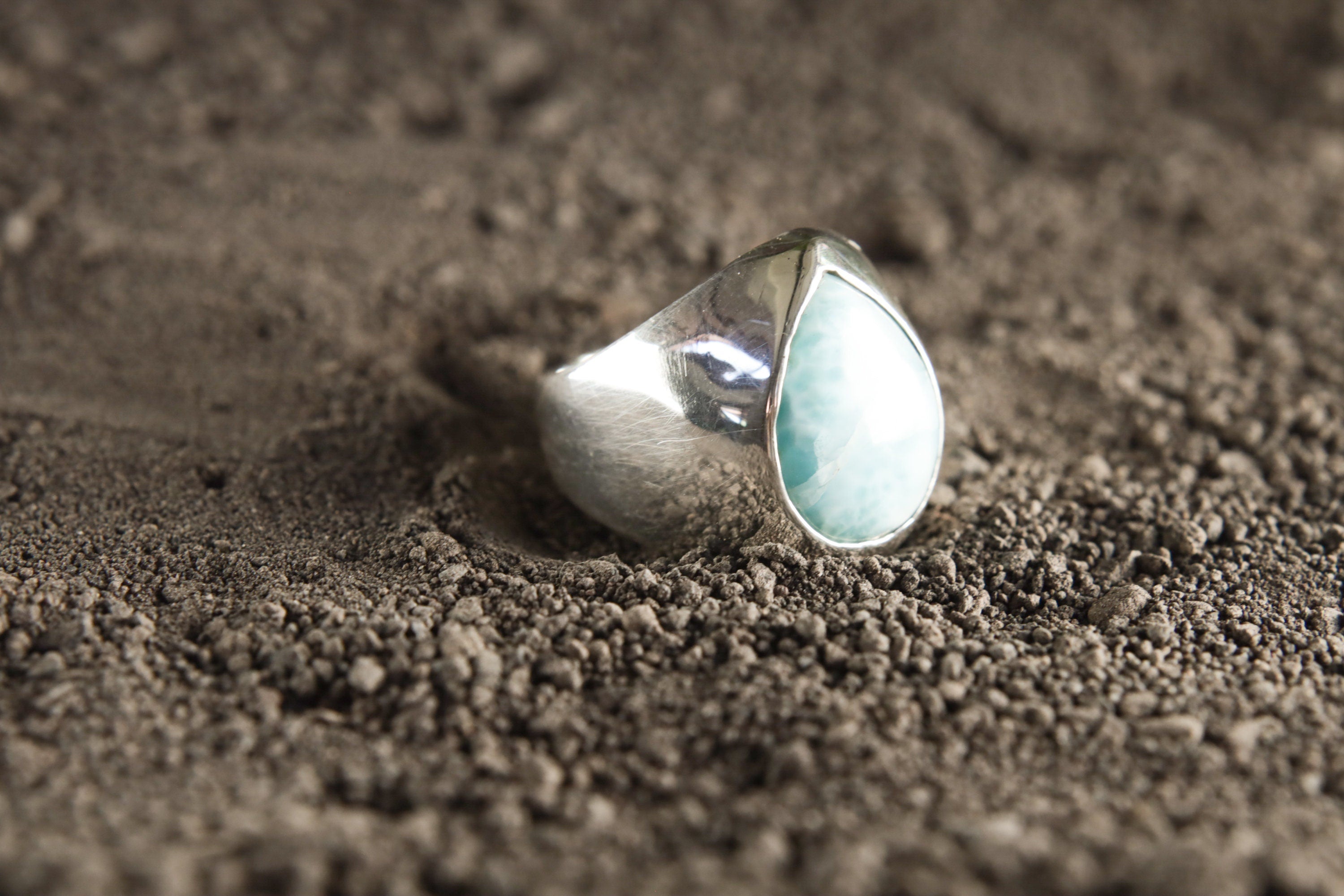 Side view of polished Larimar ring showing the raised blue cabochon, hollow silver band, and handmade statement setting.