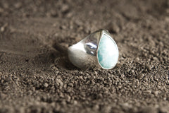 Side view of polished Larimar ring showing the raised blue cabochon, hollow silver band, and handmade statement setting.