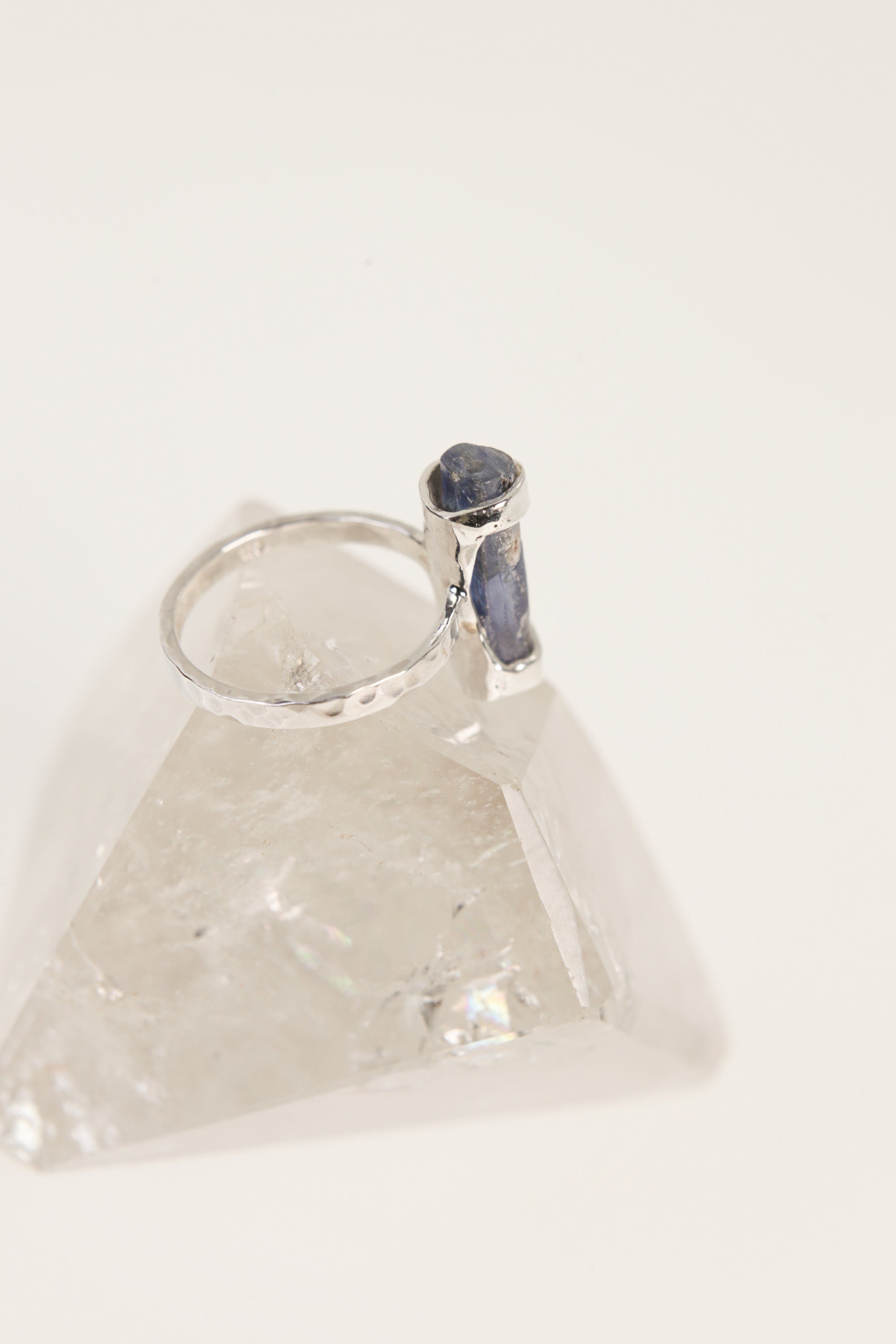 Australian Ocean Kyanite ring displayed on clear quartz, showing oxidized silver band and vertical blue gemstone setting.