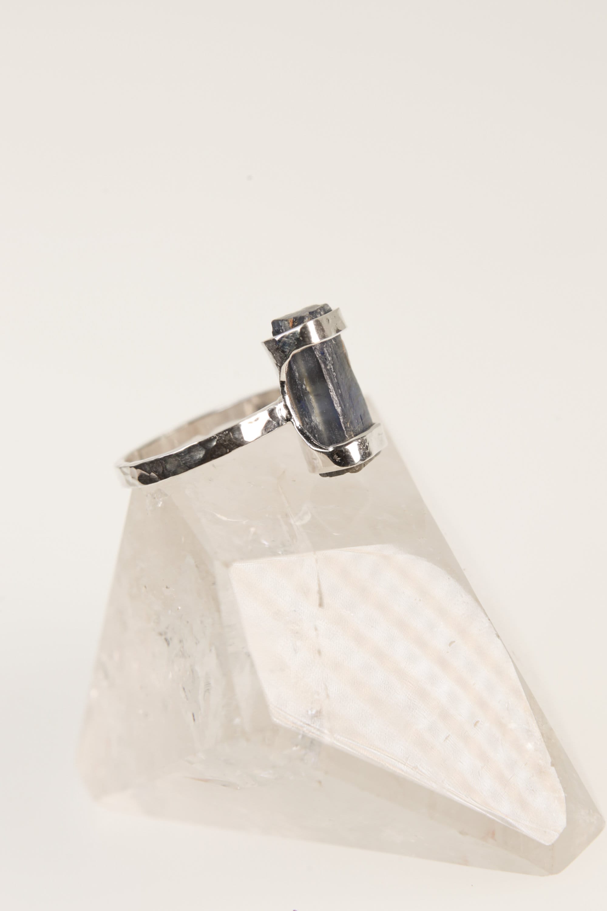 Raw Australian Ocean Kyanite ring displayed on clear quartz, with oxidized sterling silver setting and deep blue crystal.