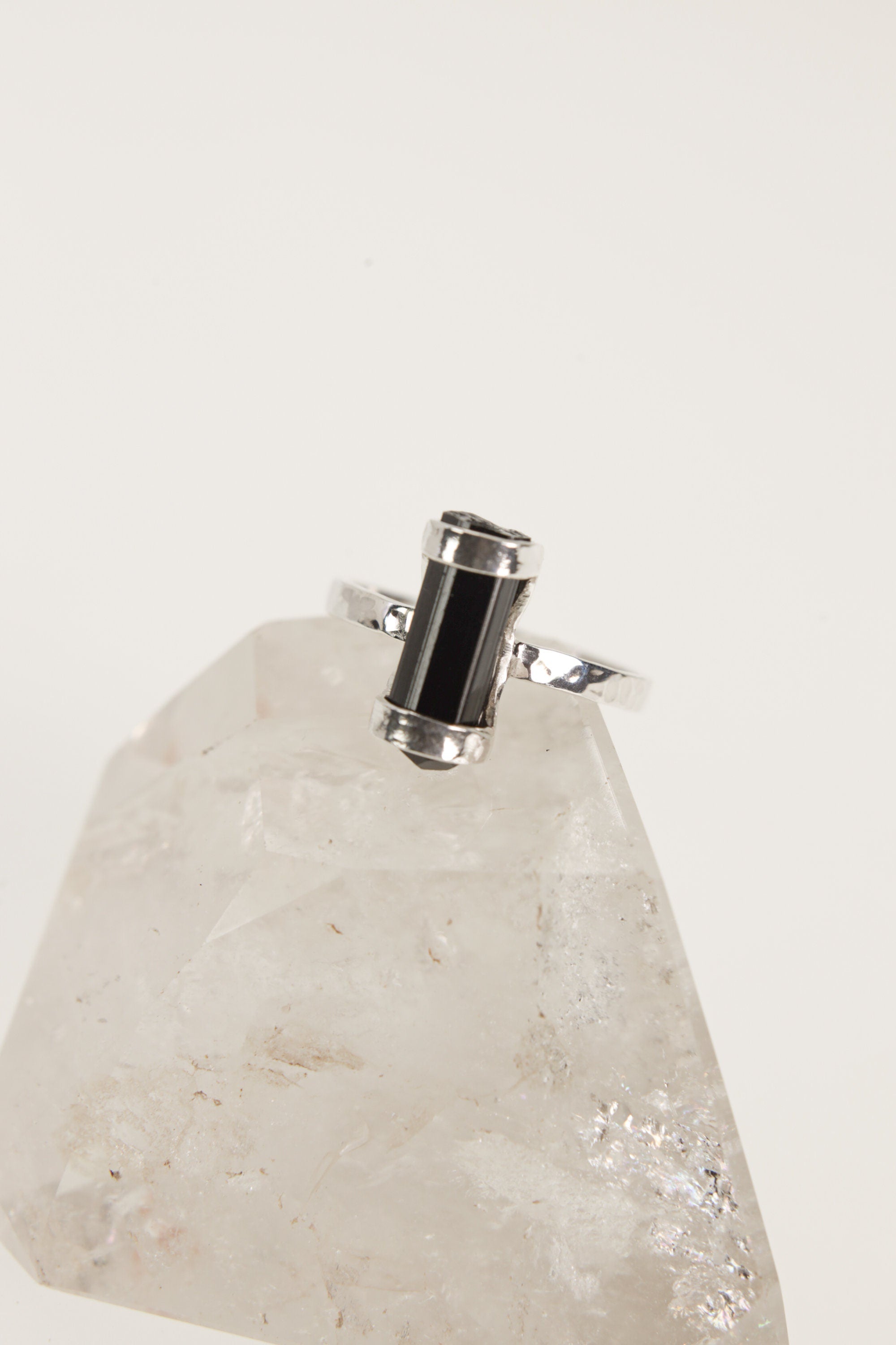Terminated Black Tourmaline Ring shown on white crystal display from the back with open silver band and black stone.