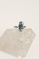 Terminated Blue Apatite ring shown on clear quartz, with hammered oxidized sterling silver and bright azure stone.