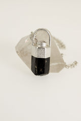 Himalayan Brown Dravite Tourmaline pendant on white background, showing dark terminated crystal and shiny sterling silver cap.