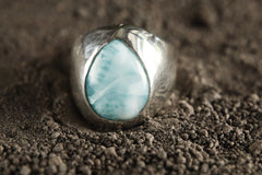 Close-up of Larimar cabochon ring showing soft blue colour, white ocean-like patterning, and polished sterling silver setting.