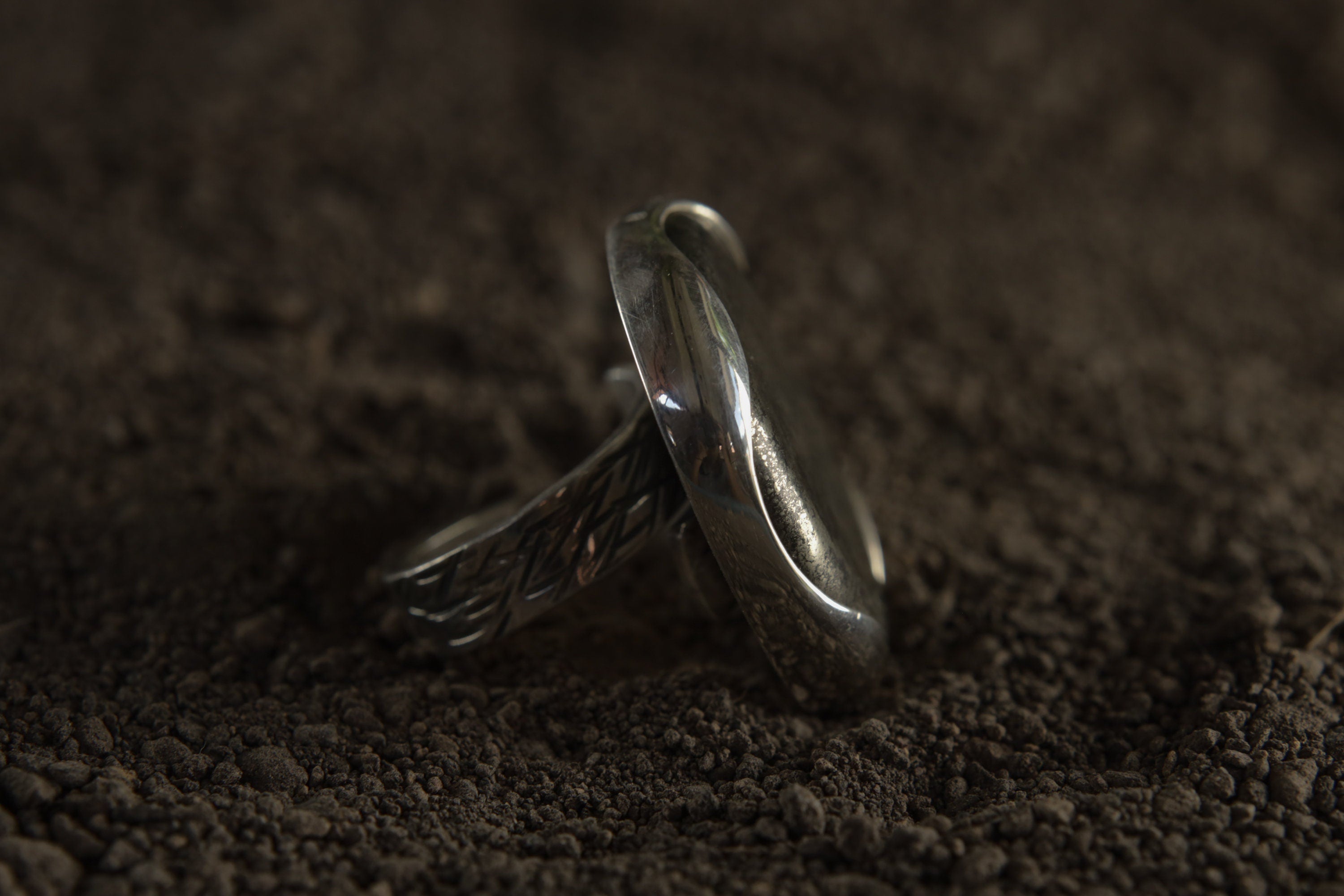 Side view of Pyrite adjustable ring showing raised waved bezel, open silver band, and polished handmade construction.