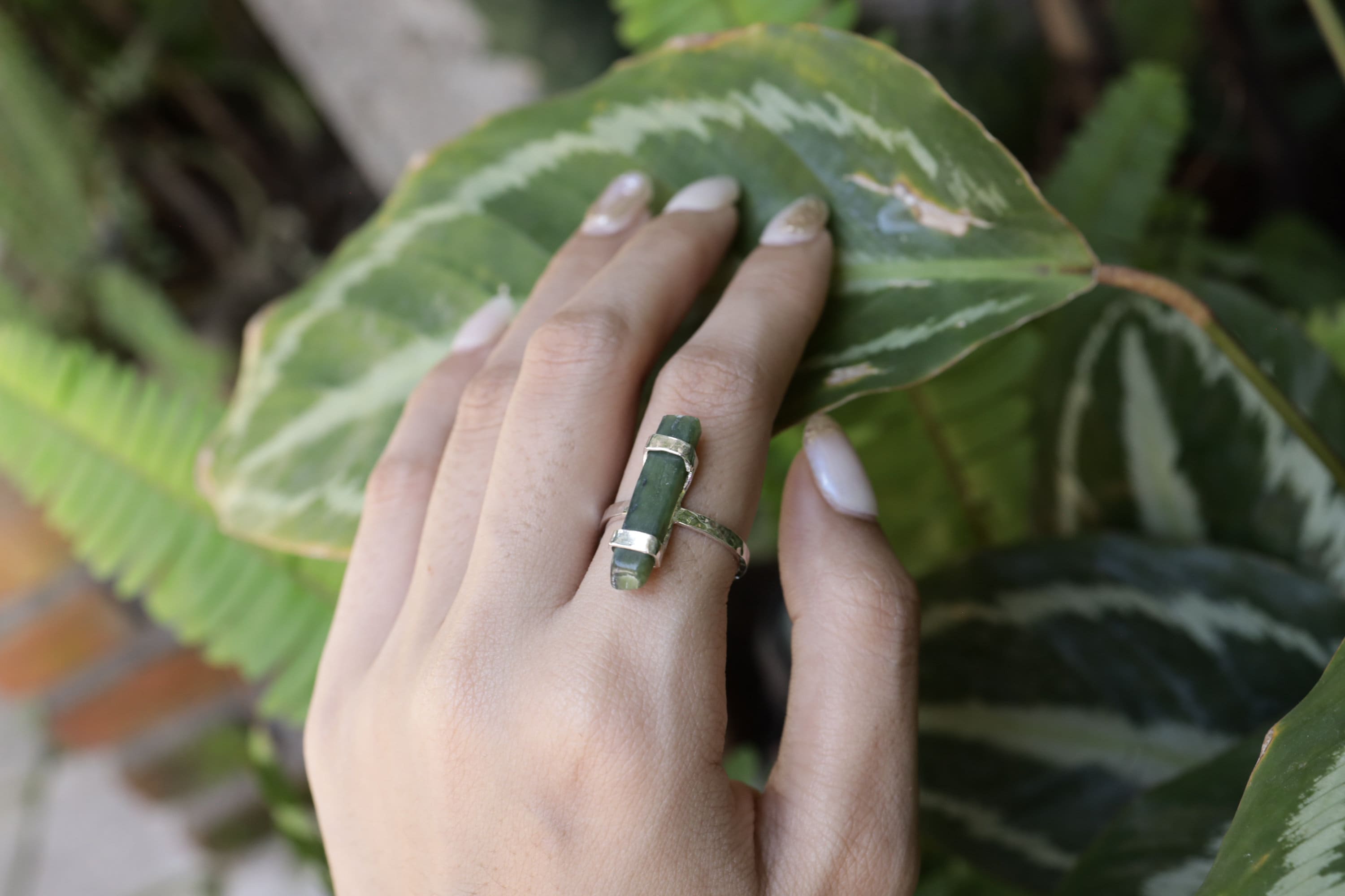 Handmade oxidized 925 sterling silver Australian Jade ring shown worn on the hand, with deep green stone and hammered band.