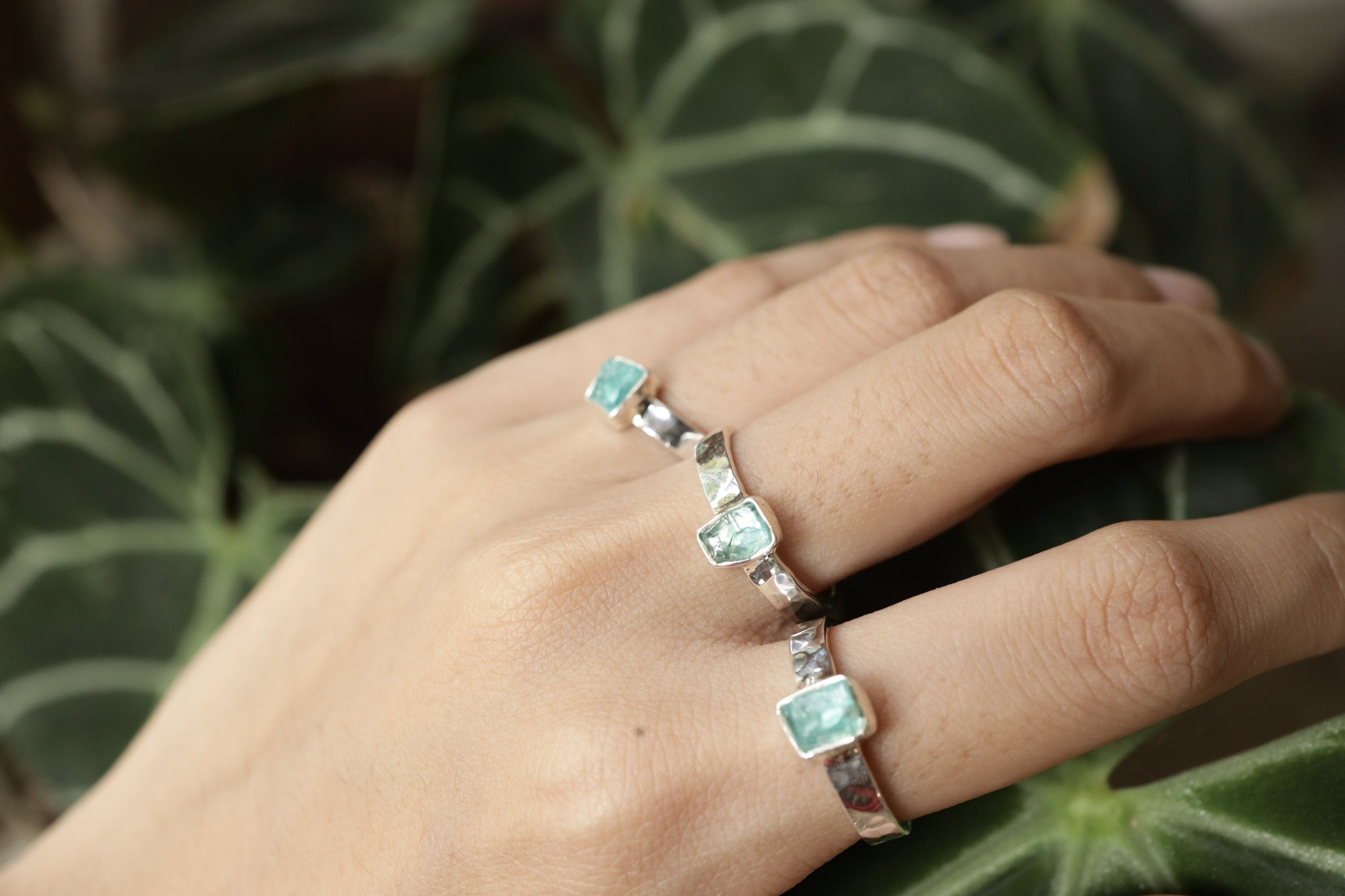 Raw Blue Apatite Gem Ring shown held with bright teal-blue stone and slim hammered silver stacking band.