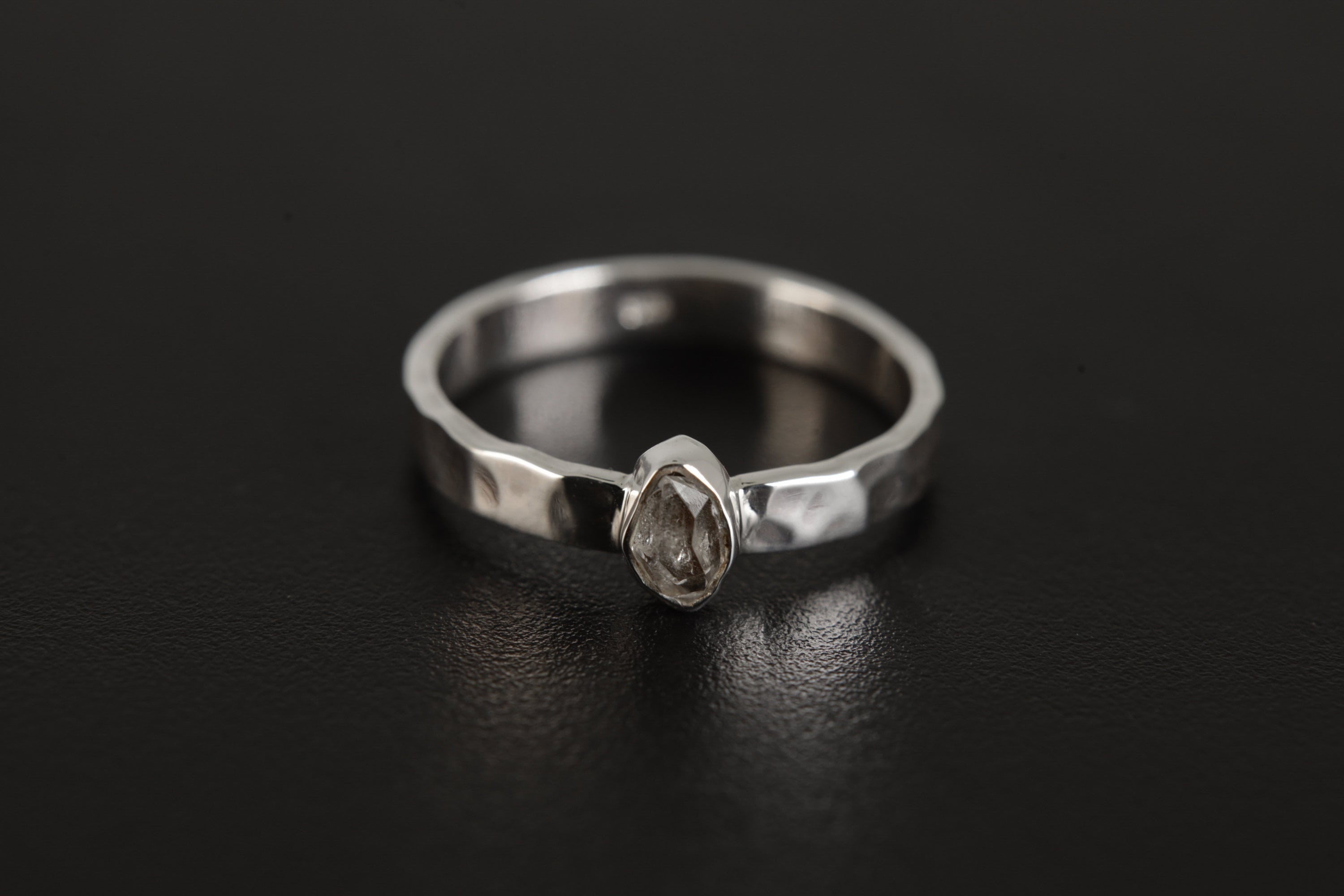 Petite Herkimer Diamond Ring shown on black background with flat sterling silver band and bright clear crystal.