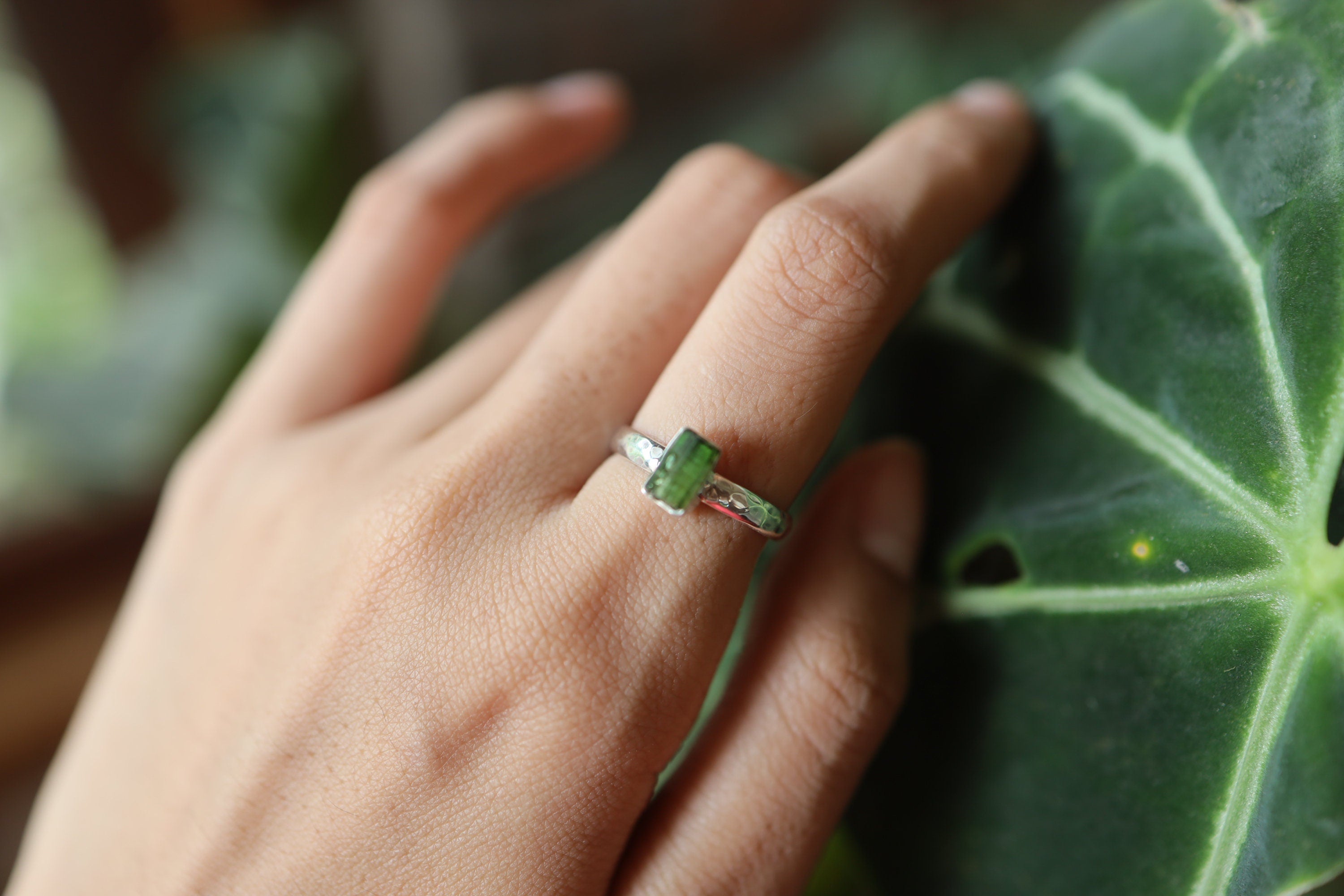 Green Tourmaline sterling silver ring shown from the side, highlighting the hammered band and upright gemstone setting.