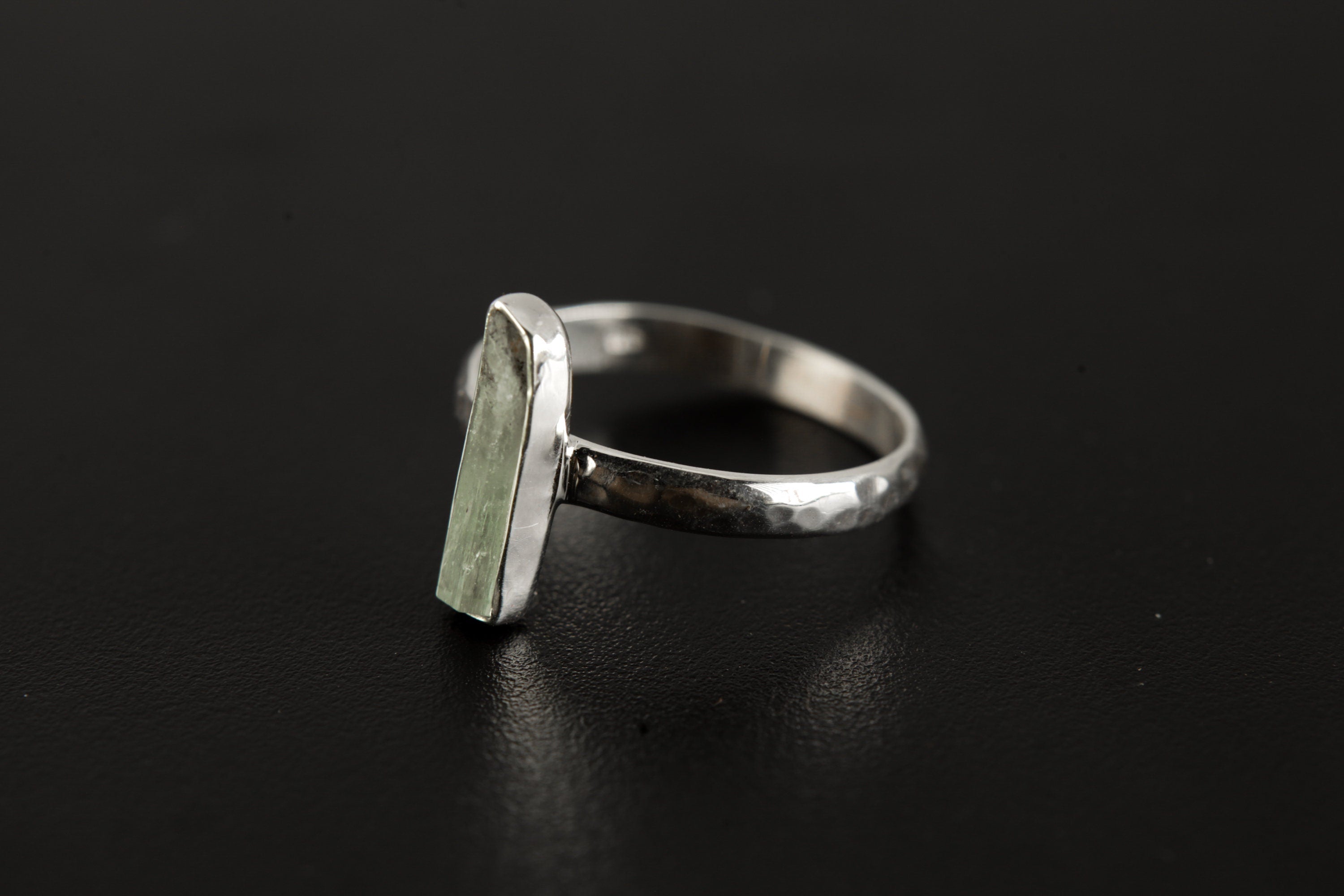 Aquamarine silver ring shown from the side, highlighting hammered sterling silver texture and long gemstone profile.
