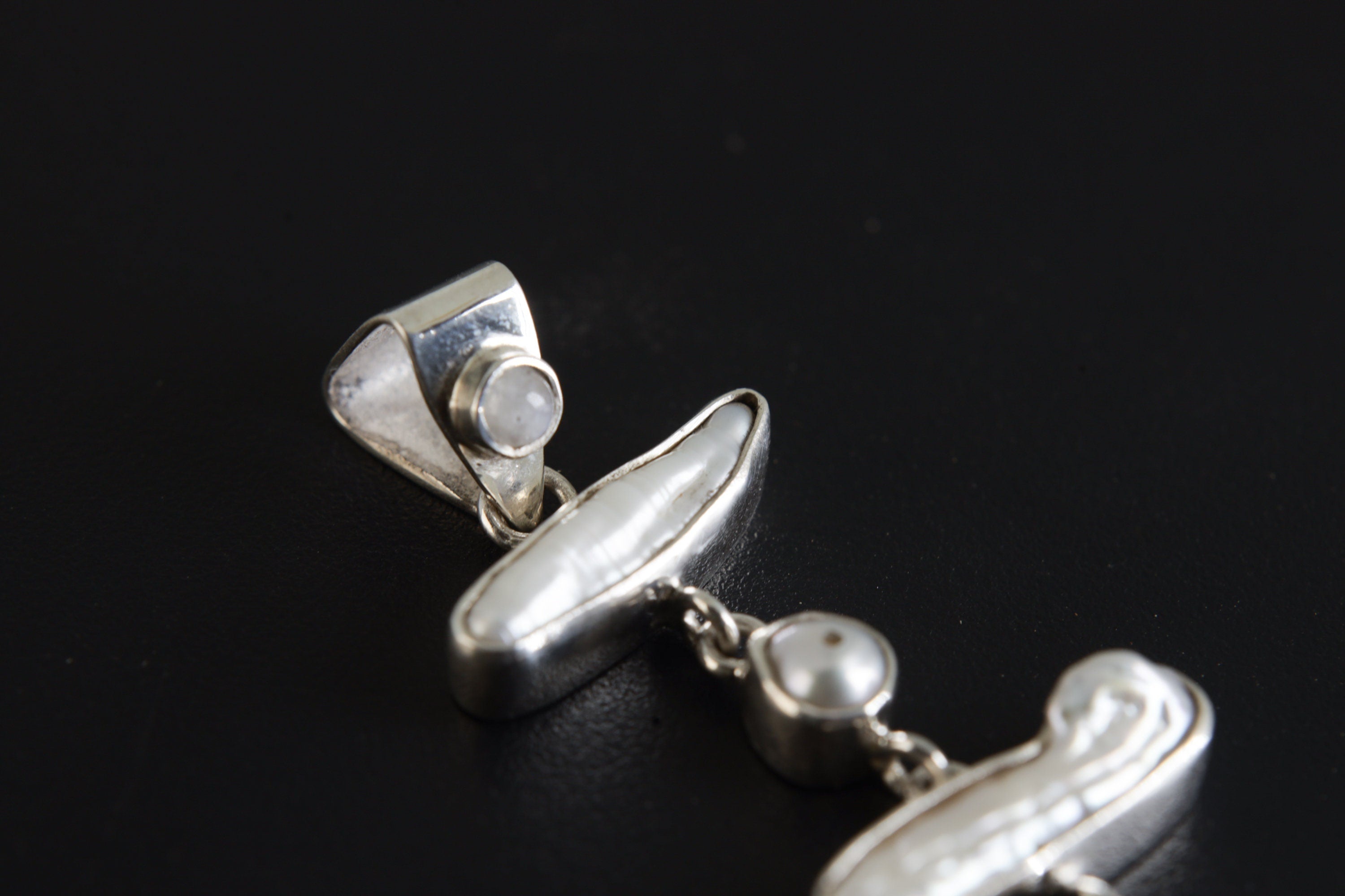 Close-up of Blue Moonstone and Pearl cascade pendant, showing triangular bail, bezel settings, and polished silver links.