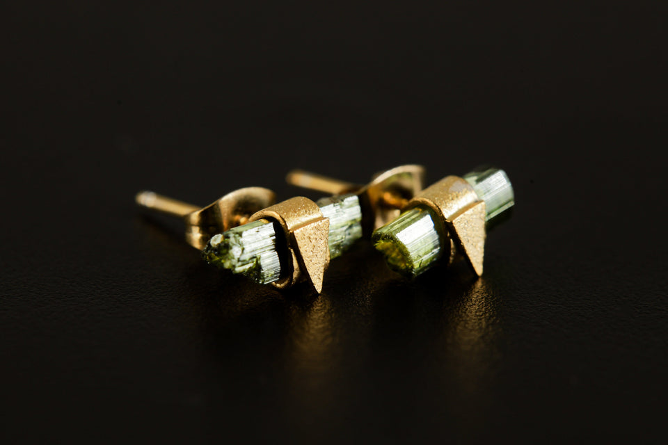Handmade Green Tourmaline stud earrings displayed on dark background with raw stones and triangle settings.