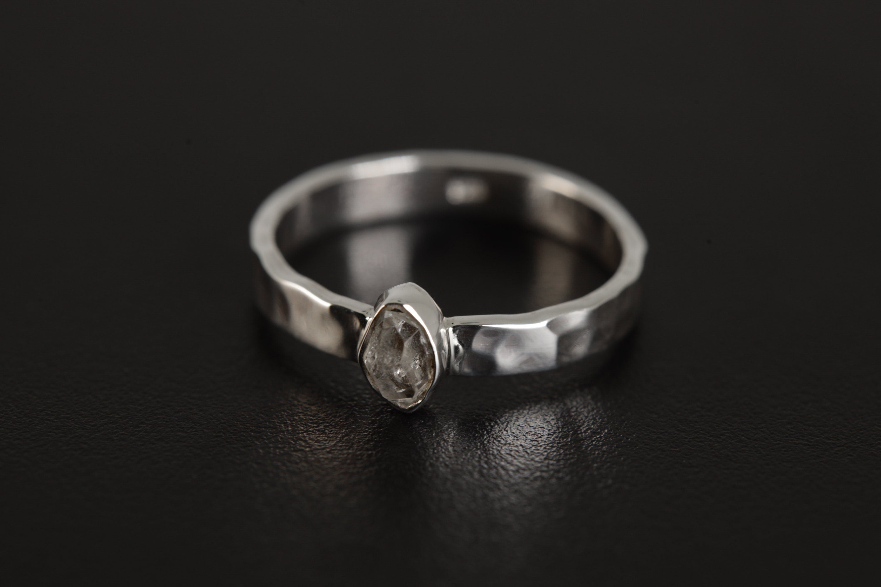 Petite Herkimer Diamond Ring shown on black background with raw double-terminated Quartz and polished silver band.