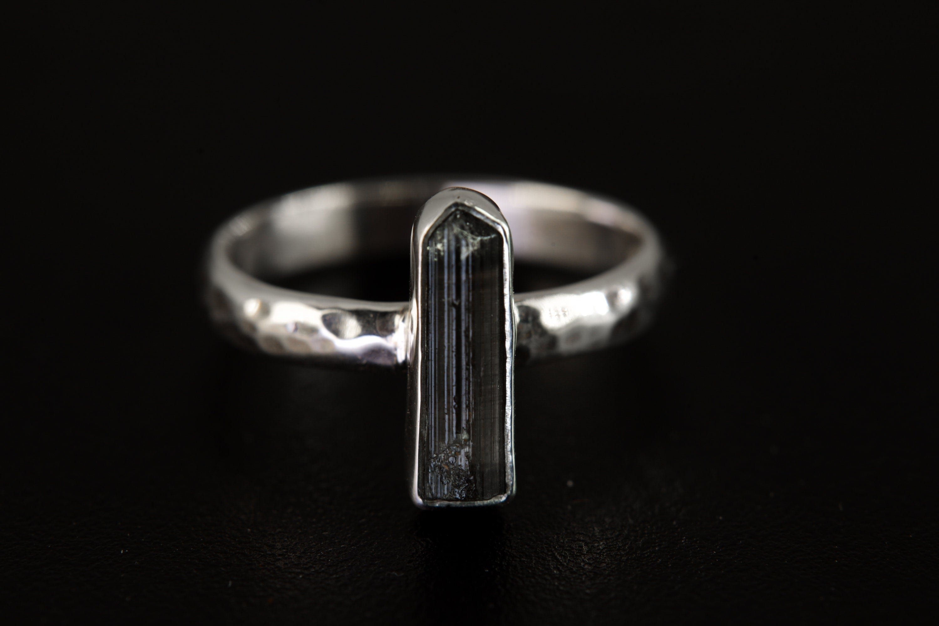 Watermelon Tourmaline ring displayed on clear quartz, showing polished silver band and vertical pink-green gemstone.