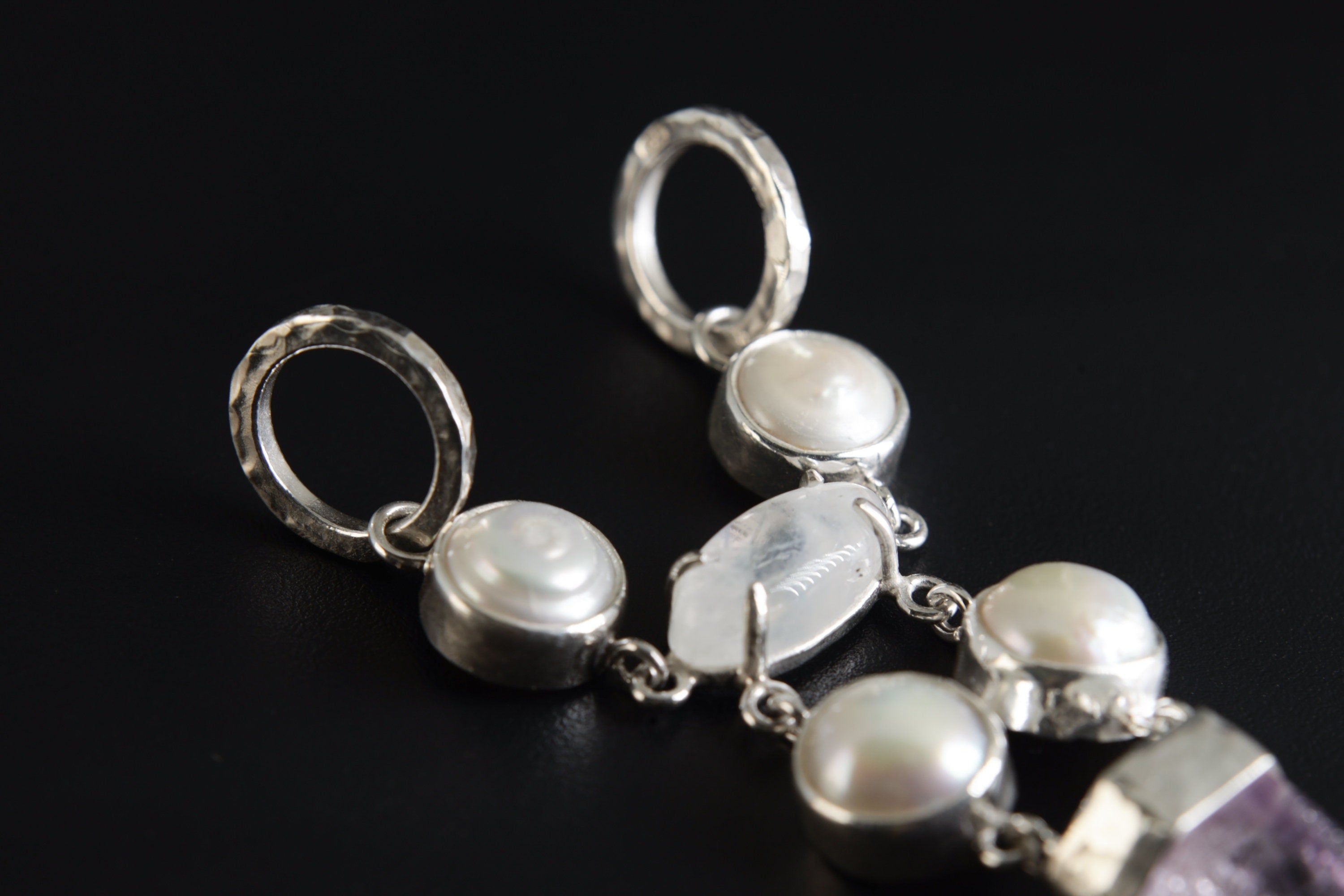 Close-up of dual-sided round bail and South Sea Pearl settings in a hammered high-shine sterling silver pendant.